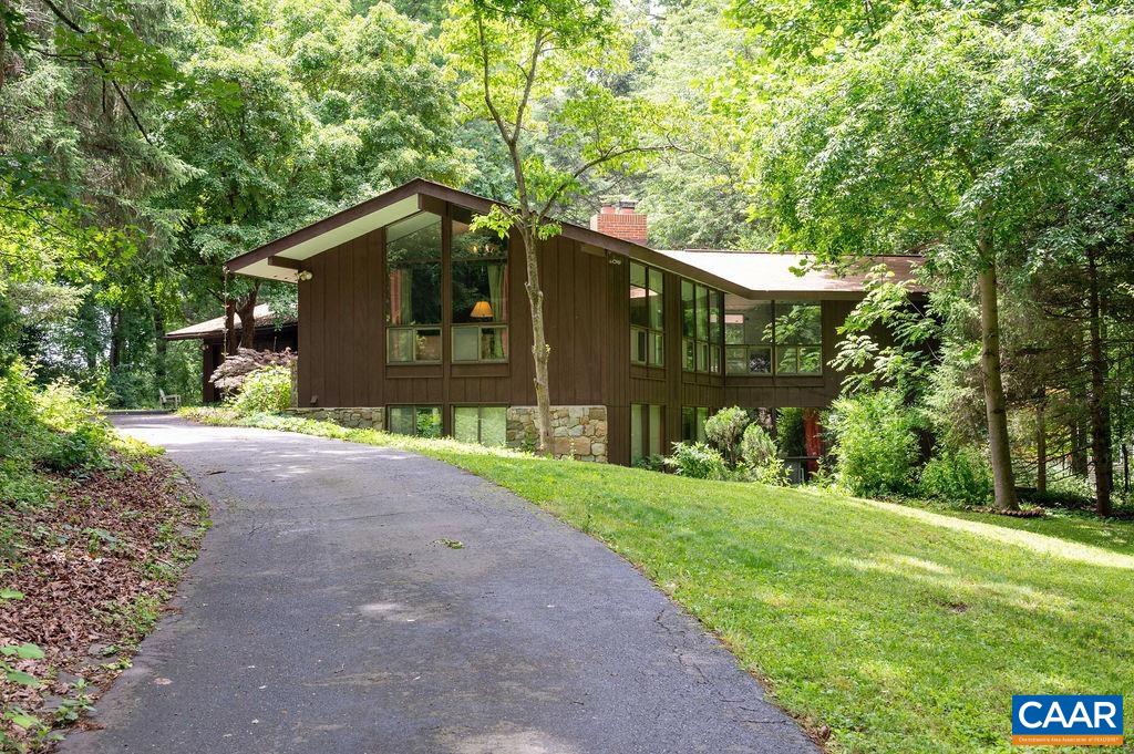 This sprawling one-of-a-kind mid-century modern home features high ceilings, a dramatic curved brick fireplace wall & extensive floor to ceiling glass, for an interior that merges with nature, all set on a gorgeous, private 1+ acre lot in one of Albemarle's in-demand neighborhoods. Four bedrooms, 2.5 baths. Main floor offers a secluded owner's suite, eat-in-kitchen w/quartz counters, formal dining & living rooms, handy office with built-ins (could be a nursery). Terrace level includes additional bedrooms, huge family room, laundry & bonus room. Outdoor living space abounds on decks, patio, sitting areas on both levels whether you want sun or shade. Fabulous deck planters overflow with roses & overlook water feature. Top it all off with a two car attached garage! Key West neighborhoods offers a (membership based) pool & tennis club, Rivanna River access, hiking trails, neighborhood events. Current owner has operated a successful homestay in lower level for extra income (buyers should verify feasability with County). Close to Darden Towe Park, shopping, and a short drive to I64 or into downtown Charlottesville. SEE FLOOR PLAN IN DOCUMENTS.