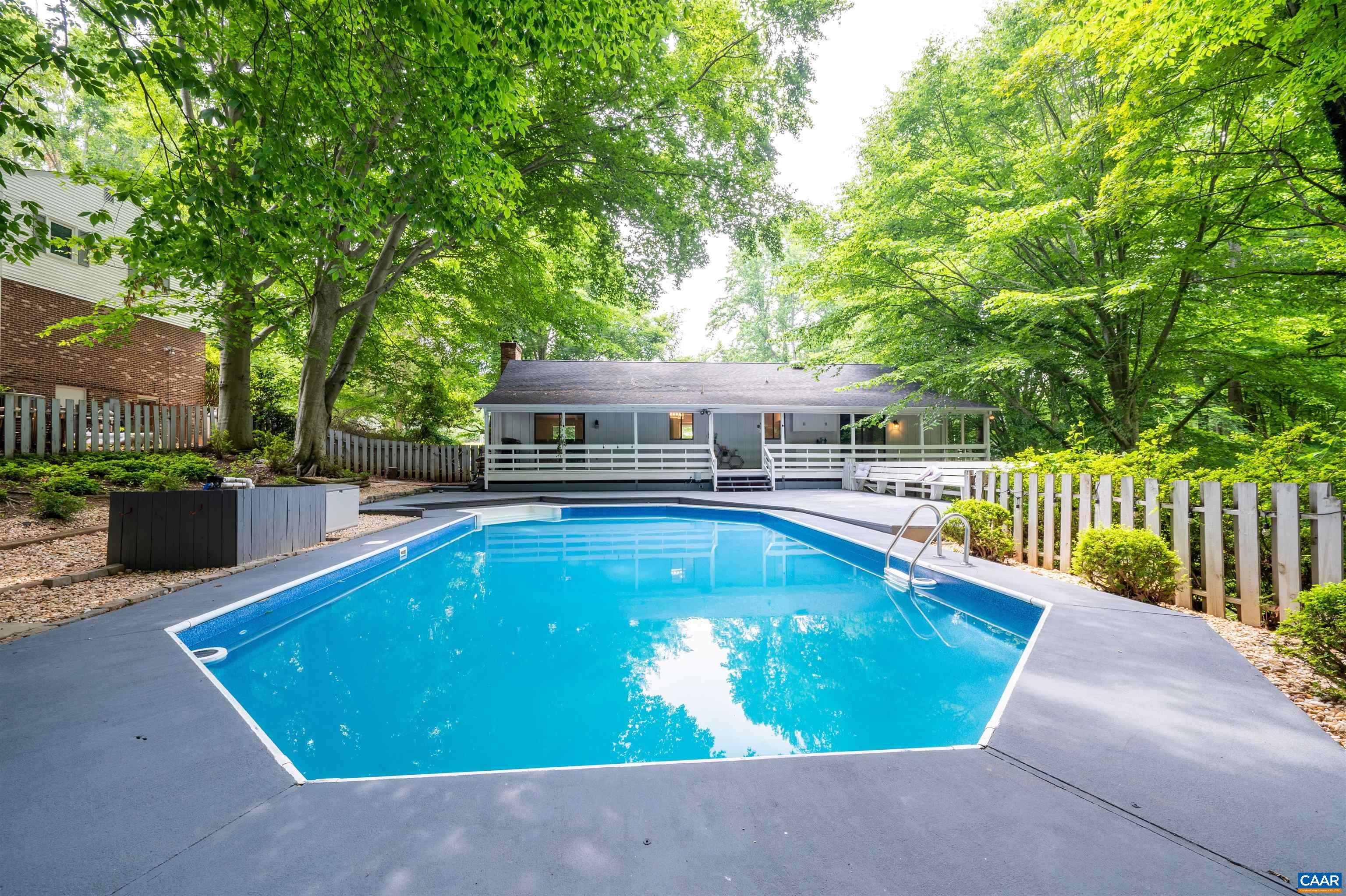 This NEWLY RENOVATED 6 bedroom, 3 bathroom, 3136 fin sq ft WOODBROOK home features TWO PRIMARY SUITES, hardwood and LVP flooring throughout, and a PRIVATE POOL with wrap-around decking and rear-facing PORCH just perfect for entertaining! The open-concept main level features a GREAT ROOM with vaulted ceilings and white-painted brick WOOD-BURNING FIREPLACE with woodstove insert, a generously-sized dining room nook, and an opened-up kitchen with pool views, PORCELAIN FARMHOUSE SINK, gorgeous BUTCHER-BLOCK COUNTERS, light-reflecting TILE BACKSPLASH, and more! Rest easy in the BRAND NEW LOWER-LEVEL PRIMARY SUITE featuring a private fireplace, shiplap accent wall, seating area/office nook, and ensuite luxurious primary bath with two separate vanities and walk-in closet! Enjoy being CONVENIENTLY LOCATED within walking distance to Woodbrook Elementary, 8 minutes to Ivy Creek Foundation, and 15 minutes from UVA, the hospital, and the historic Downtown Mall!