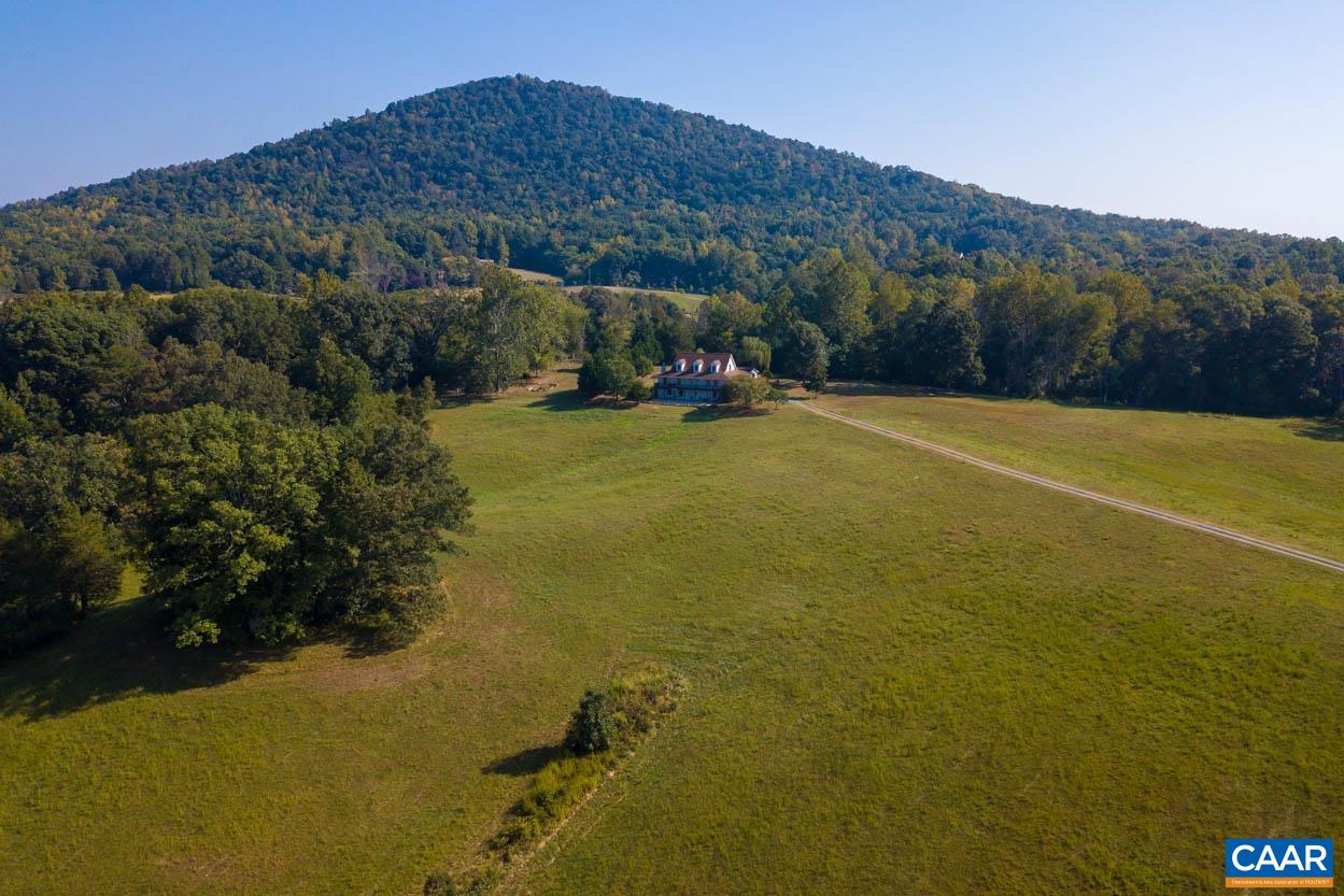 Elim Farm is a picturesque 26-acre property with panoramic mountain views in the heart of Free Union. With Buck Mountain as a backdrop, the existing house sits on a knoll overlooking the surrounding hillsides and mountain tops to the south and west.  The home, built in 2006, has a traditional floor plan and features locally sourced pine floors and a lovely stone fireplace. The main level includes formal living and dining spaces, a charming farmhouse kitchen and primary suite with a private sunroom. The property is mostly cleared with some wooded areas running along the perimeter. A variety of magnificent trees and nice rock outcroppings dot the edge of the front field with a small pond and creek at the bottom of hill. Unlimited potential for expansion with a perfect level building site for a future pool, barn or house that would capture even bigger mountain views.  Magnificent sunsets, Western Albemarle Schools, high speed internet and only 15 minutes to Barracks Road or 29N Shopping.