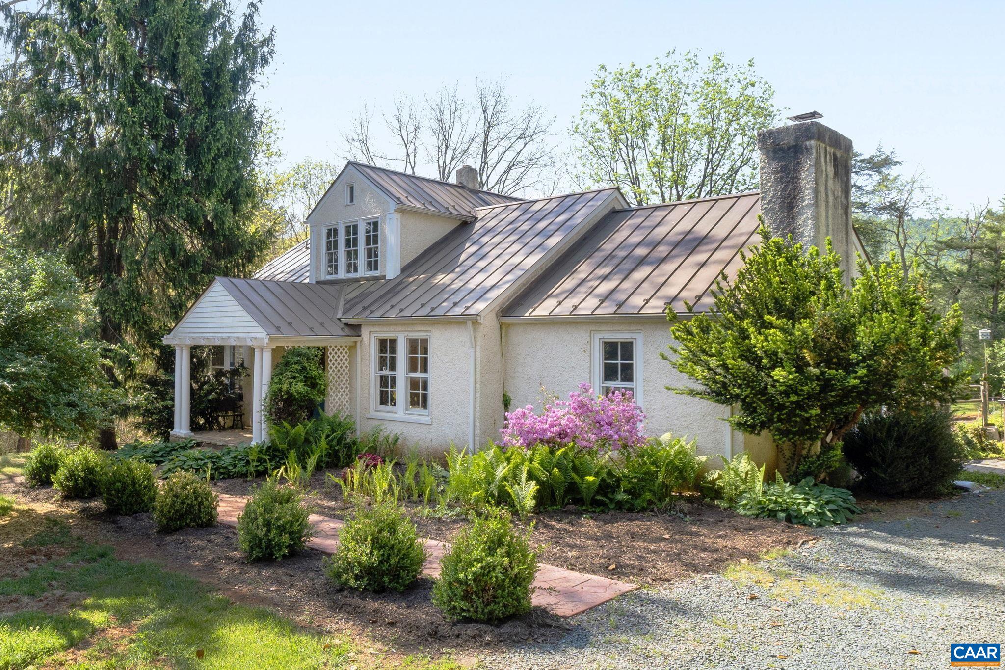 First time on the market for this charming stucco abode featuring beautiful heart pine and oak hardwood floors, fresh interior paint, and so many fantastic spaces for entertaining both inside and out. On the main level find a large living room, a cozy den with wood-burning fireplace, three bedrooms, and a full bath. A light-filled tiled sunroom/dining room looks out over the deck and gardens and opens to the home's gourmet kitchen featuring granite counters and a Kitchen Aid dual-fuel range. Oak stairs lead to the spacious primary suite upstairs, boasting its own sitting room, full bath with separate shower and cast iron tub, expansive walk-in closet, and balcony overlooking backyard. Outside entertaining spaces include a tiered back deck, and stone patio with outdoor kitchen space - complete with plumbed vintage cast iron sink and the perfect spot for an outdoor grill. Attic closets and a massive unfinished basement provide ample storage spaces. The yard is a gardener's dream, complete with mower, tool, and potting sheds. Whole house generator! Enjoy the Saunders Trail across the street leading to Monticello, or pop down the road to the new Biscuit Run Park, the county's newest and largest park with 1,190 acres to explore.