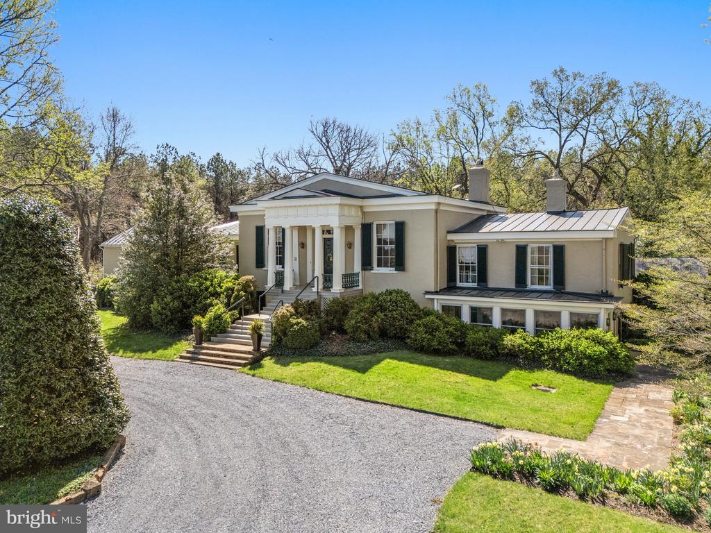 The stunning and historic estate of Ashleigh, ca. 1840 is rich in history, and beautifully sited to enjoy the magnificent gardens as well as grand views of the Delaplane countryside. These 98 acres were once part of Oak Hill, Chief Justice John Marshall's estate, and the stone and stucco Greek Revival Manor house was designed and built for his granddaughter, Margaret Marshall Smith and her husband. Ashleigh is listed on both the National Register of Historic Places and Virginia Historic Landmarks. To further protect the estate, the current owners put Ashleigh into a conservation easement with The Land Trust of Virginia. Wide stairs ascend to the columned front portico, from there one enters the grand front hall. Some exquisite details of the hall include beautiful heart pine flooring and wide moldings, large, deep-set windows, and a ceiling height of over 12'. Through deep set, heart pine doorways, one then enters the elegant double drawing room adorned with a fireplace at each end of the room, a wet bar, and floor to ceiling triple sash windows which open onto decorative iron balconies. From the windows one overlooks the lower-level stone terrace with fountain, gardens, and lawn. The upper level of the east wing, in addition to b