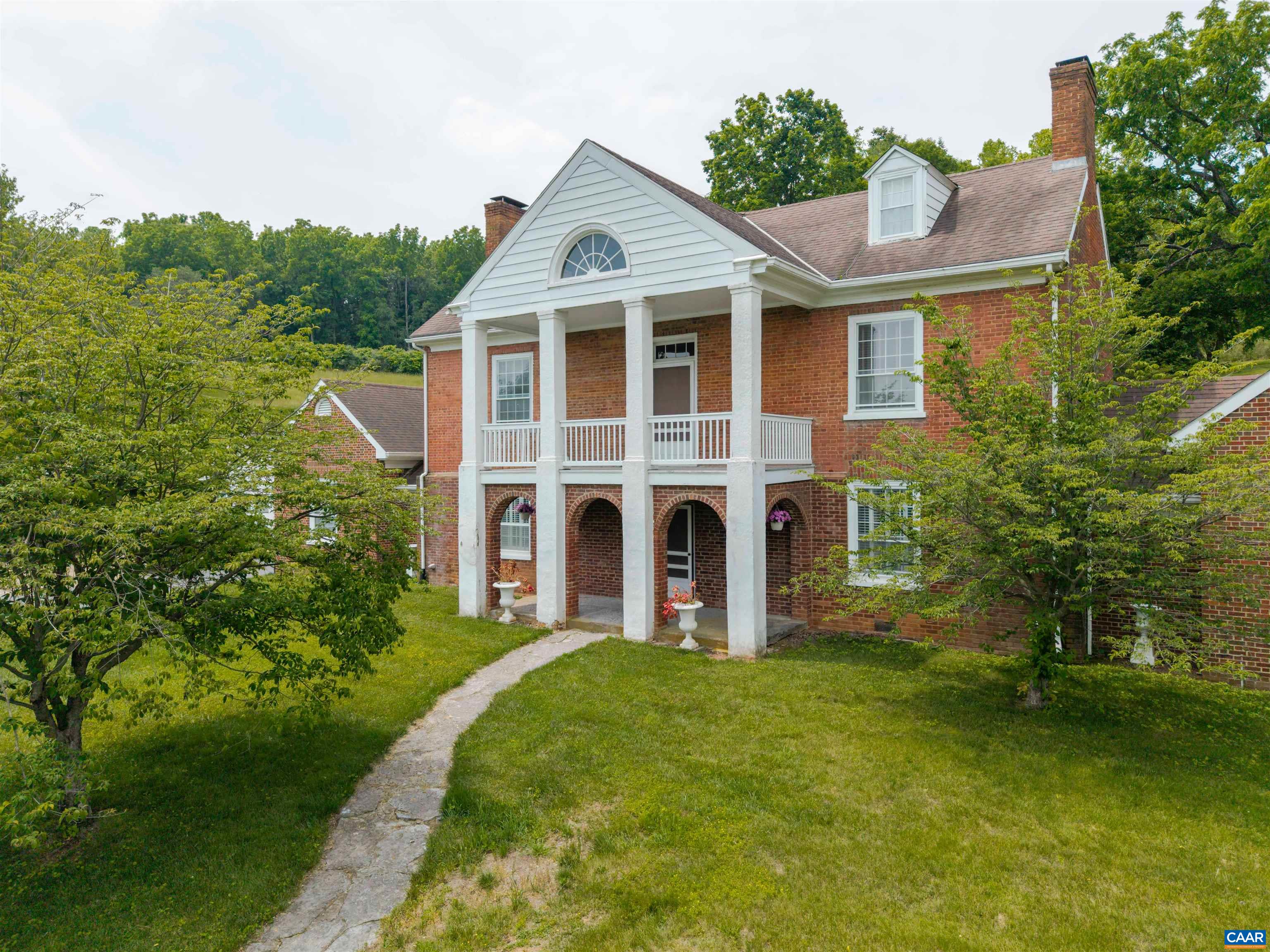 Welcome to Bellefonte, a historic home with modern amenities, perfectly located between the downtown arts and restaurant district, and easy access to two interstates. Residential zoning, with B1-C overlay and acreage, offers your choice of private retreat, home-based business, or development potential. Built on the original 1790 settlement, the house dates to 1834 with expansions and upgrades in the 1940s and ’70s. Over 4,500 sq ft of timeless elegance includes: high ceilings, hardwood floors, original wood-burning fireplaces in the living/dining rooms, a custom-built bar in the great room, and a kitchen with pantry and adjoining greenhouse. The main-level owner’s suite, with screened porch, connects discreetly to a spacious laundry, while two additional en-suite bedrooms upstairs, plus three more bedrooms on the third floor, lend themselves beautifully to a boutique B&B configuration under existing zoning. Savor pastoral views from any of four gracious porches, or retreat to the private rear walled courtyard. A 1,590 sq ft detached studio with loft and half bath presents endless possibilities for a home office, guest suite, or income-producing venture. Bellefonte is history, charm, and potential, perfectly located and preserved.