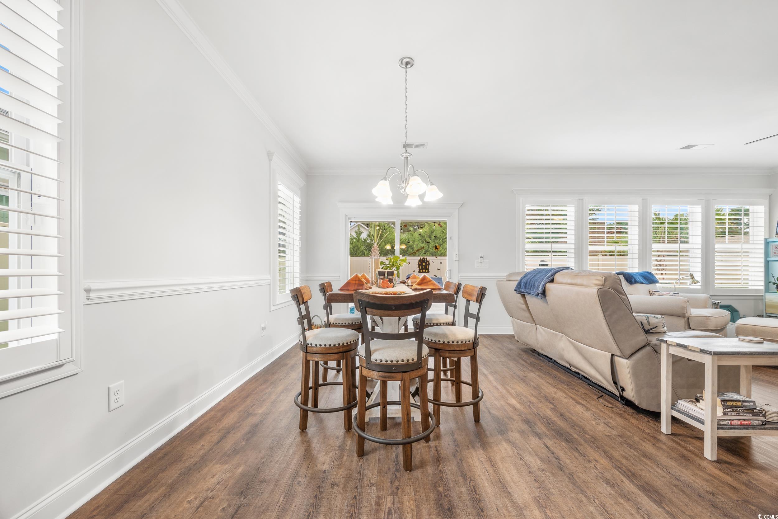 Dining space featuring a notable chandelier, ornamental molding, and dark hardwood / wood-style flooring
