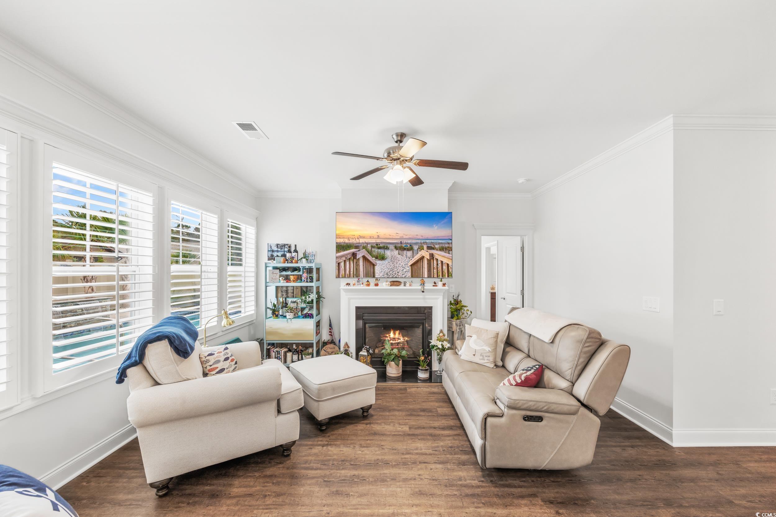 Living room with crown molding, dark hardwood / wood-style floors, and ceiling fan