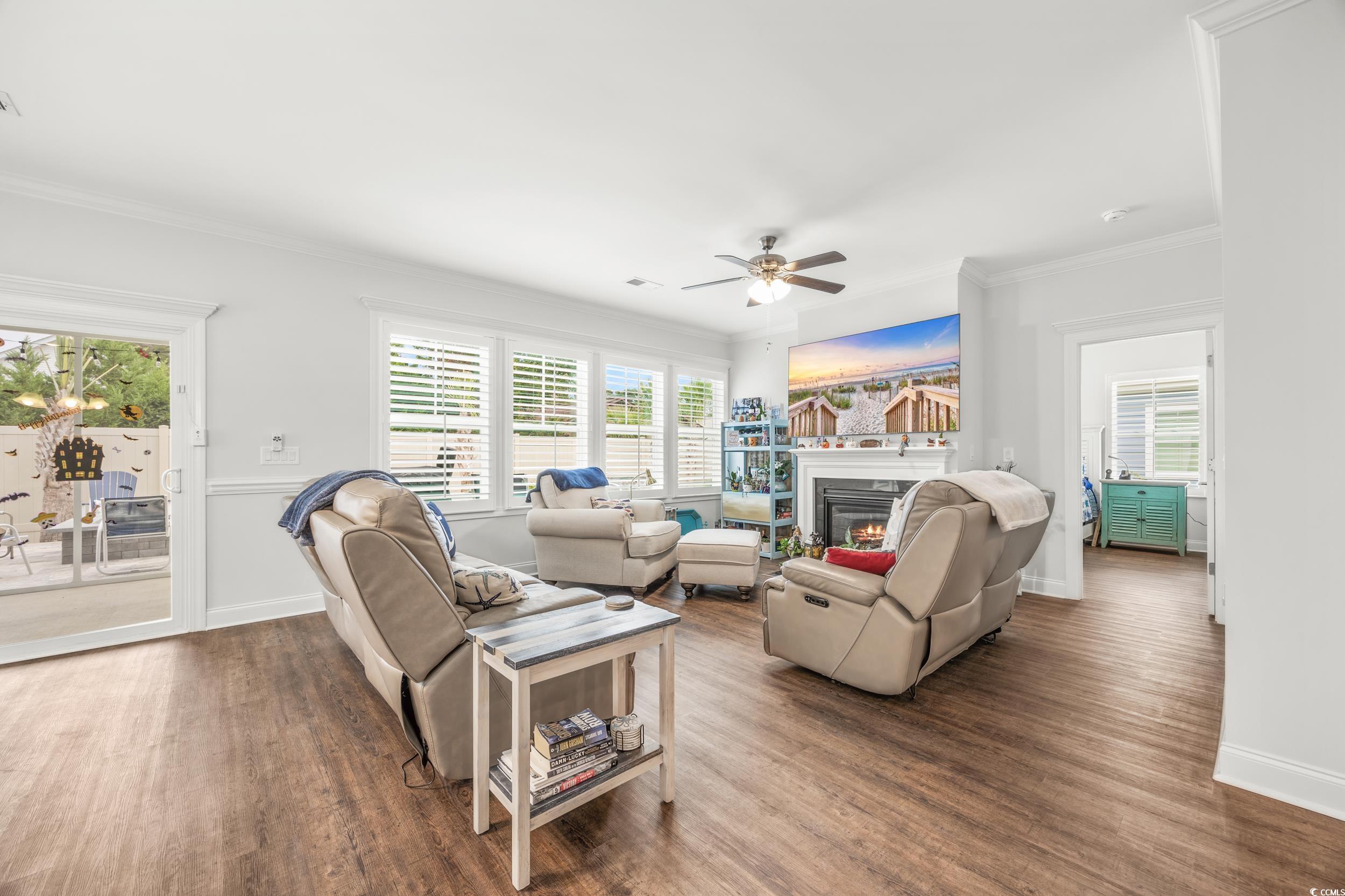 Living room featuring ceiling fan, crown molding, a wealth of natural light, and dark hardwood / wood-style floors