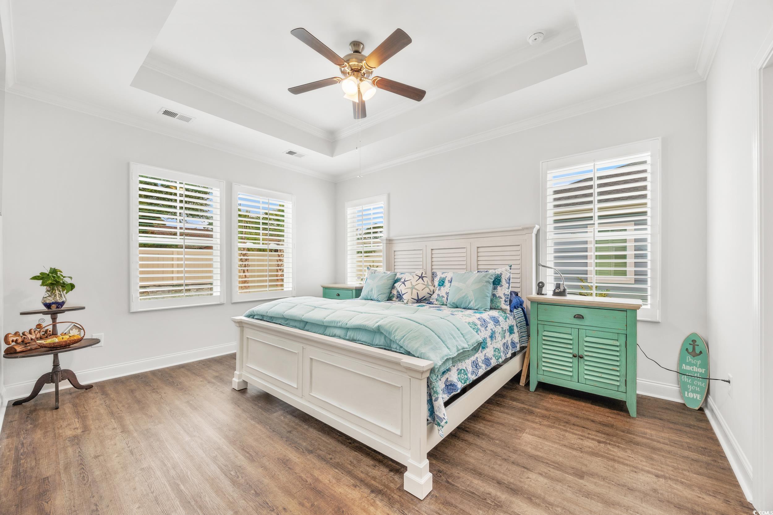 Bedroom featuring ceiling fan, a raised ceiling, ornamental molding, and hardwood / wood-style floors