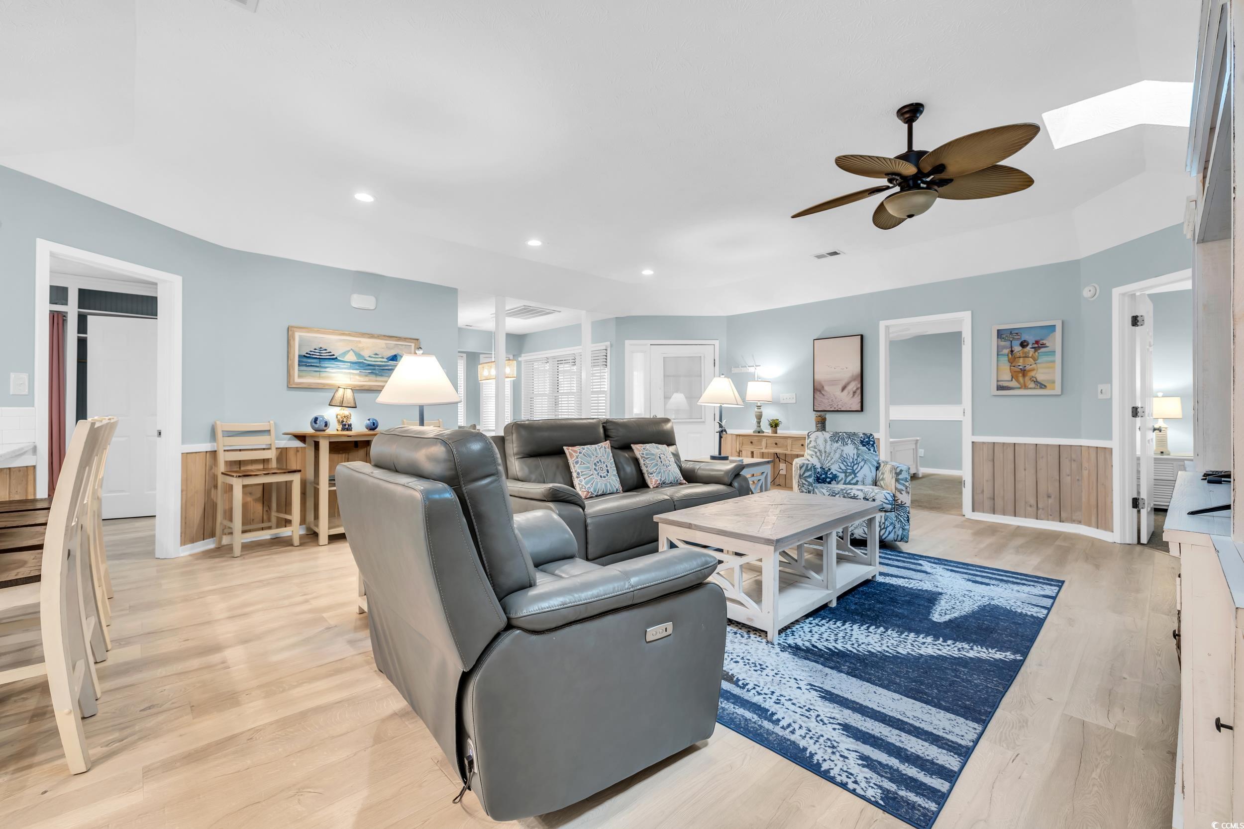Living room featuring a skylight, light hardwood / wood-style flooring, and ceiling fan
