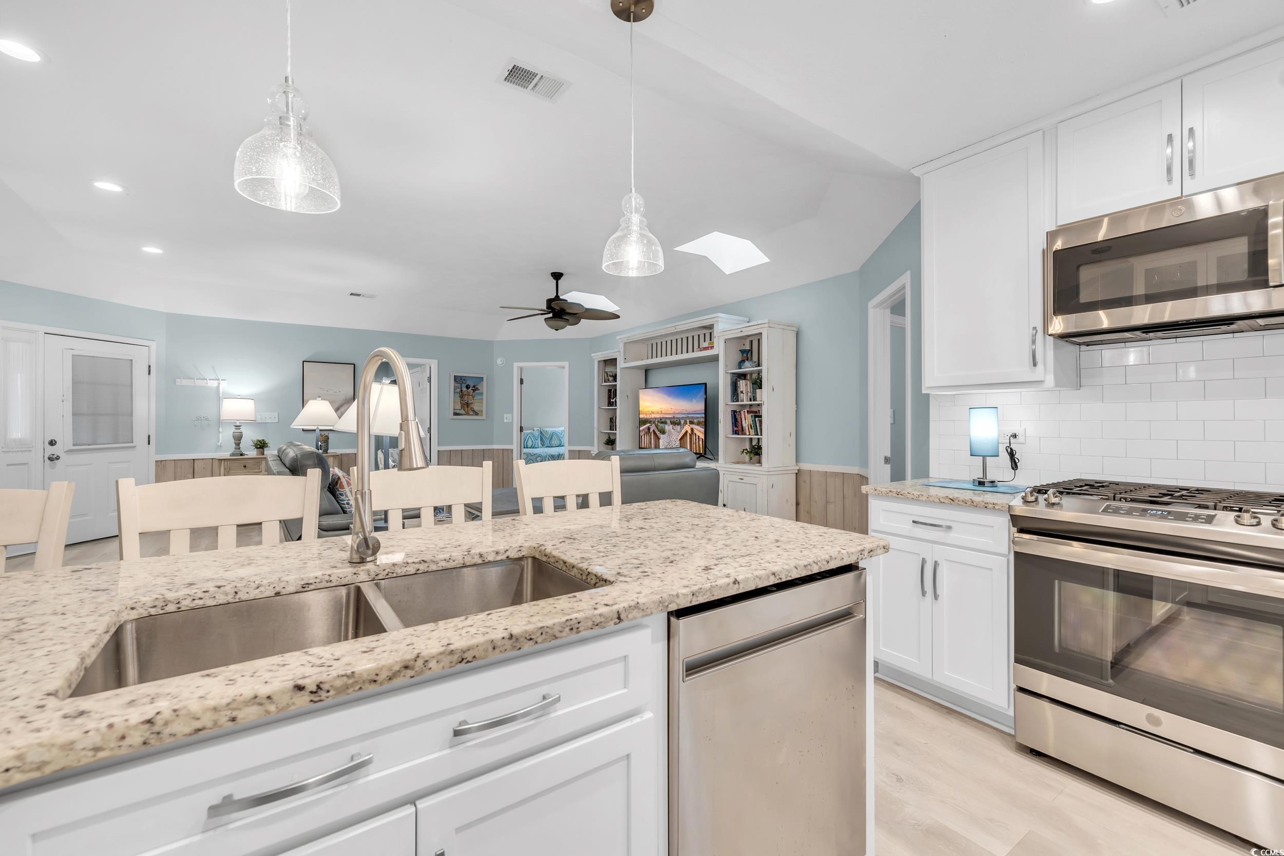 Kitchen featuring white cabinetry, sink, pendant lighting, and appliances with stainless steel finishes
