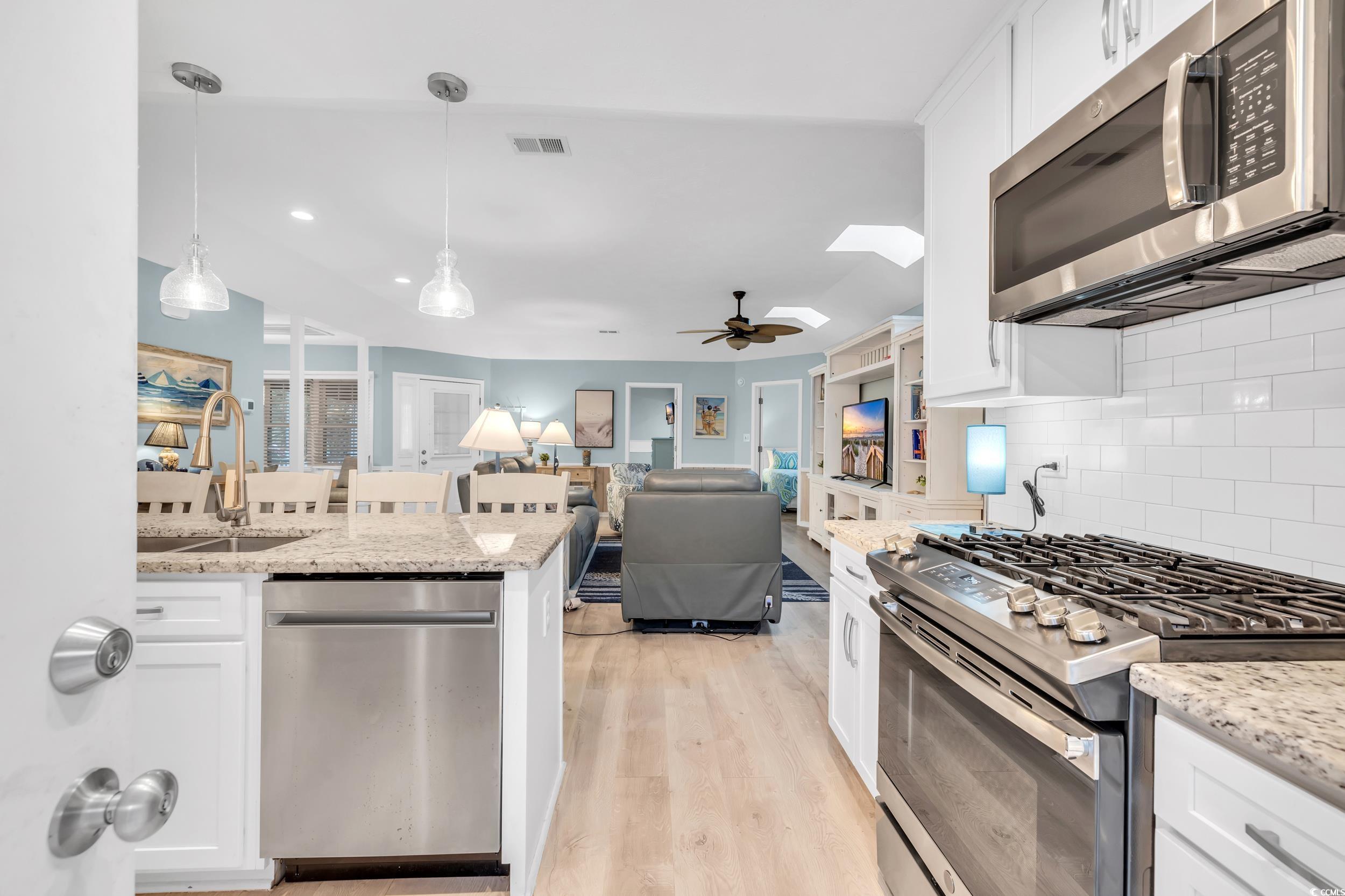 Kitchen featuring white cabinetry, sink, pendant lighting, and appliances with stainless steel finishes