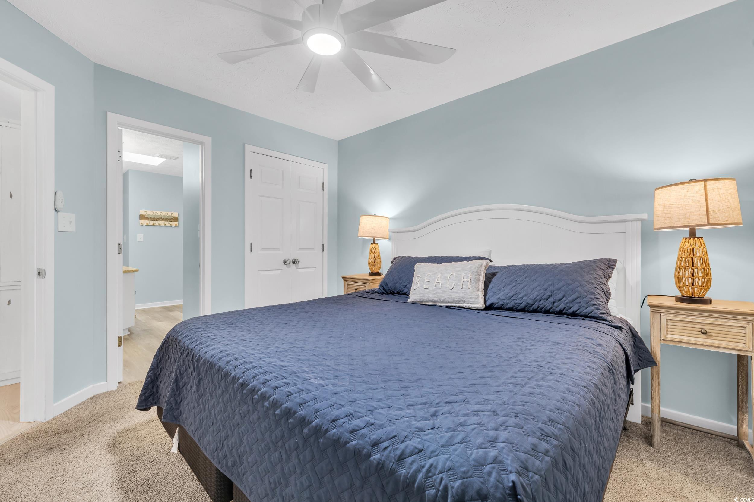 Bedroom with ceiling fan, a closet, and light carpet