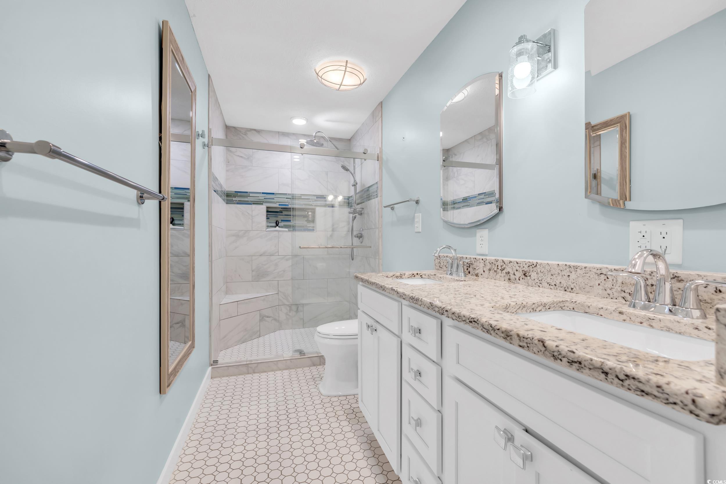 Bathroom with vanity, a shower with door, and toilet
