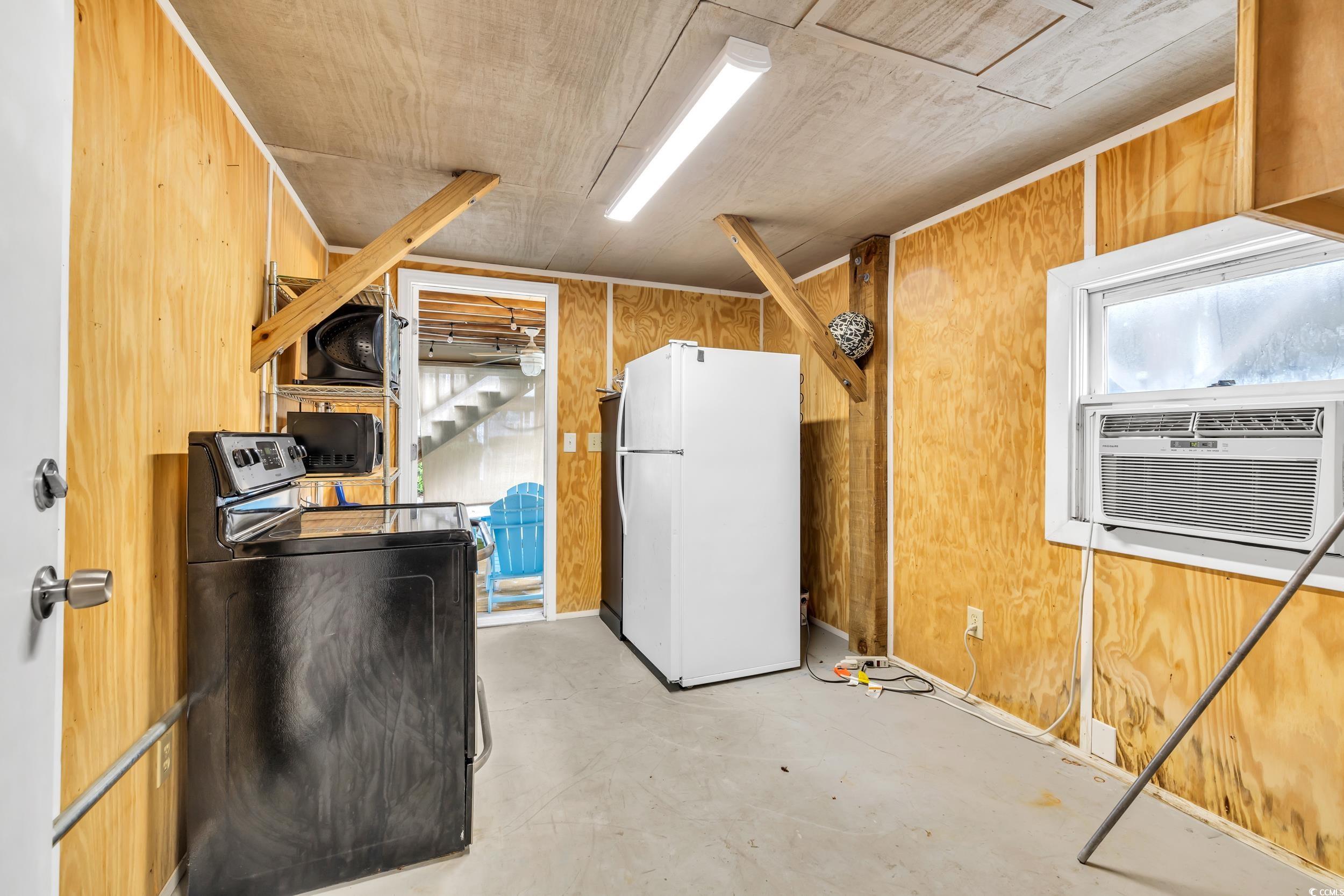 Basement with white refrigerator, wooden walls, washer / dryer, and cooling unit