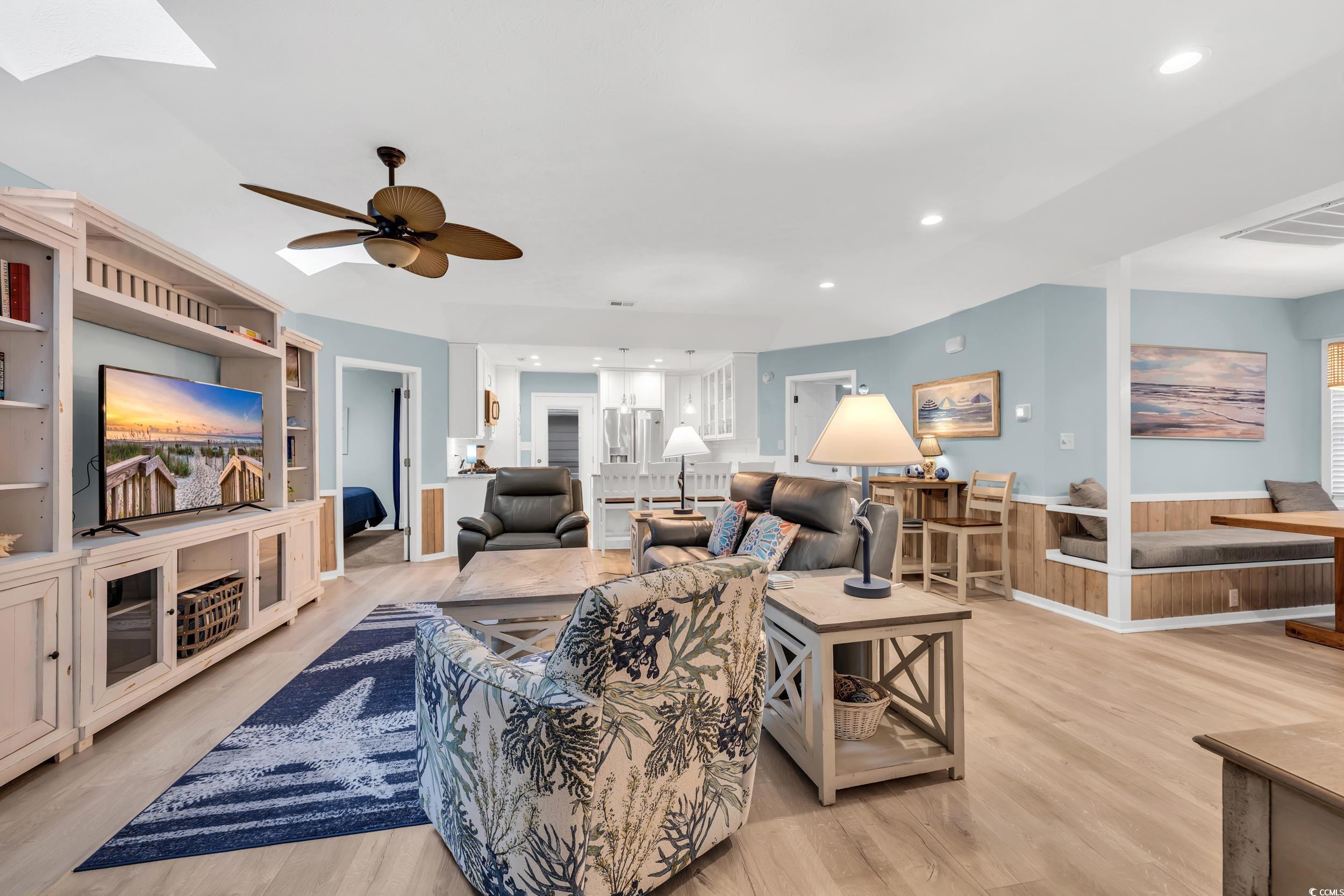 Living room with built in shelves, ceiling fan, and light wood-type flooring