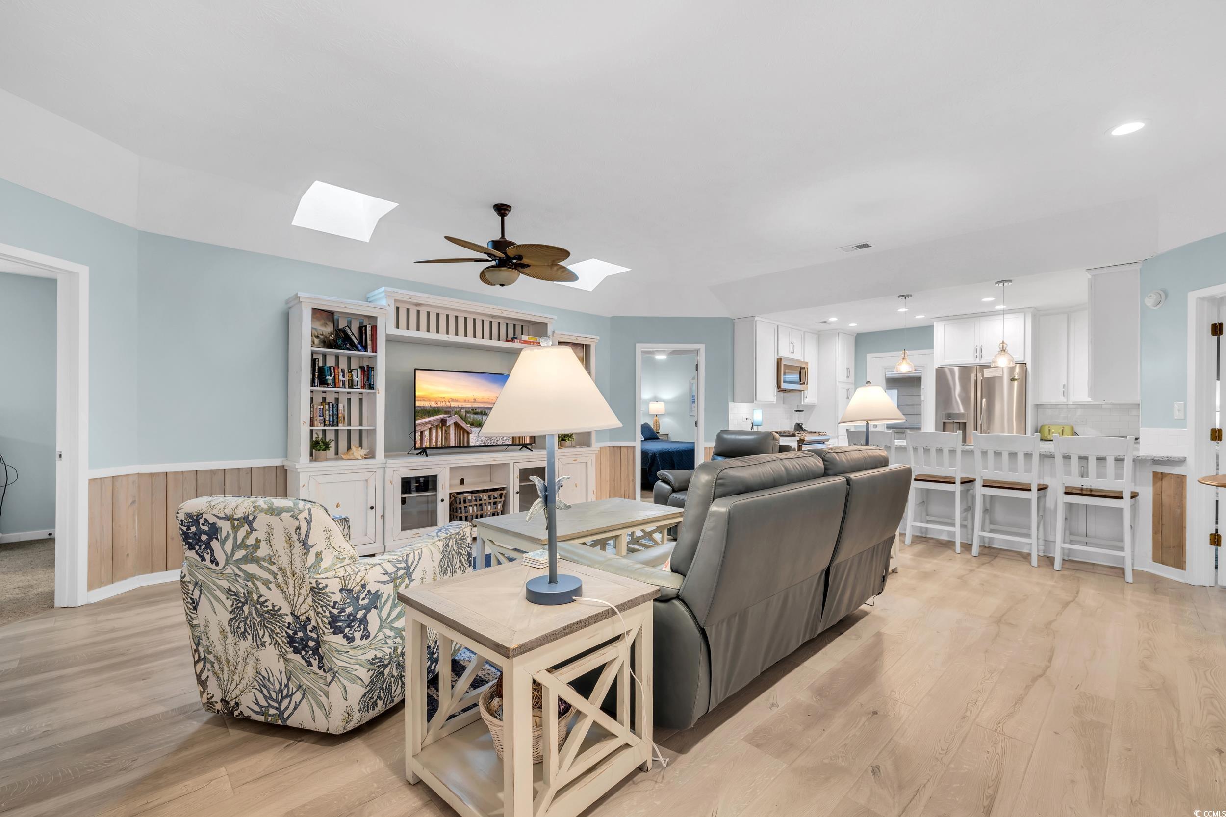 Living room featuring ceiling fan, light wood-type flooring, and a skylight