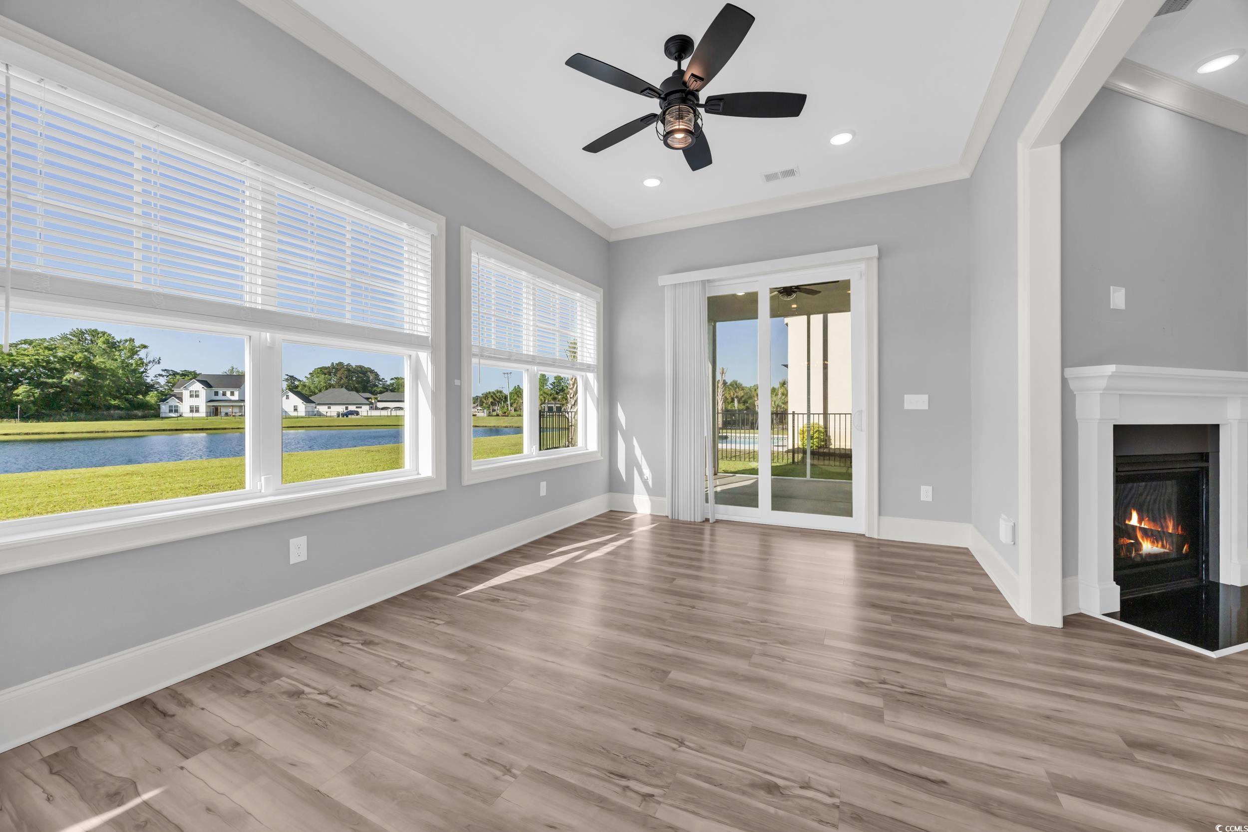 Unfurnished living room featuring a ceiling fan, crown molding, wood finished floors, baseboards, and recessed lighting