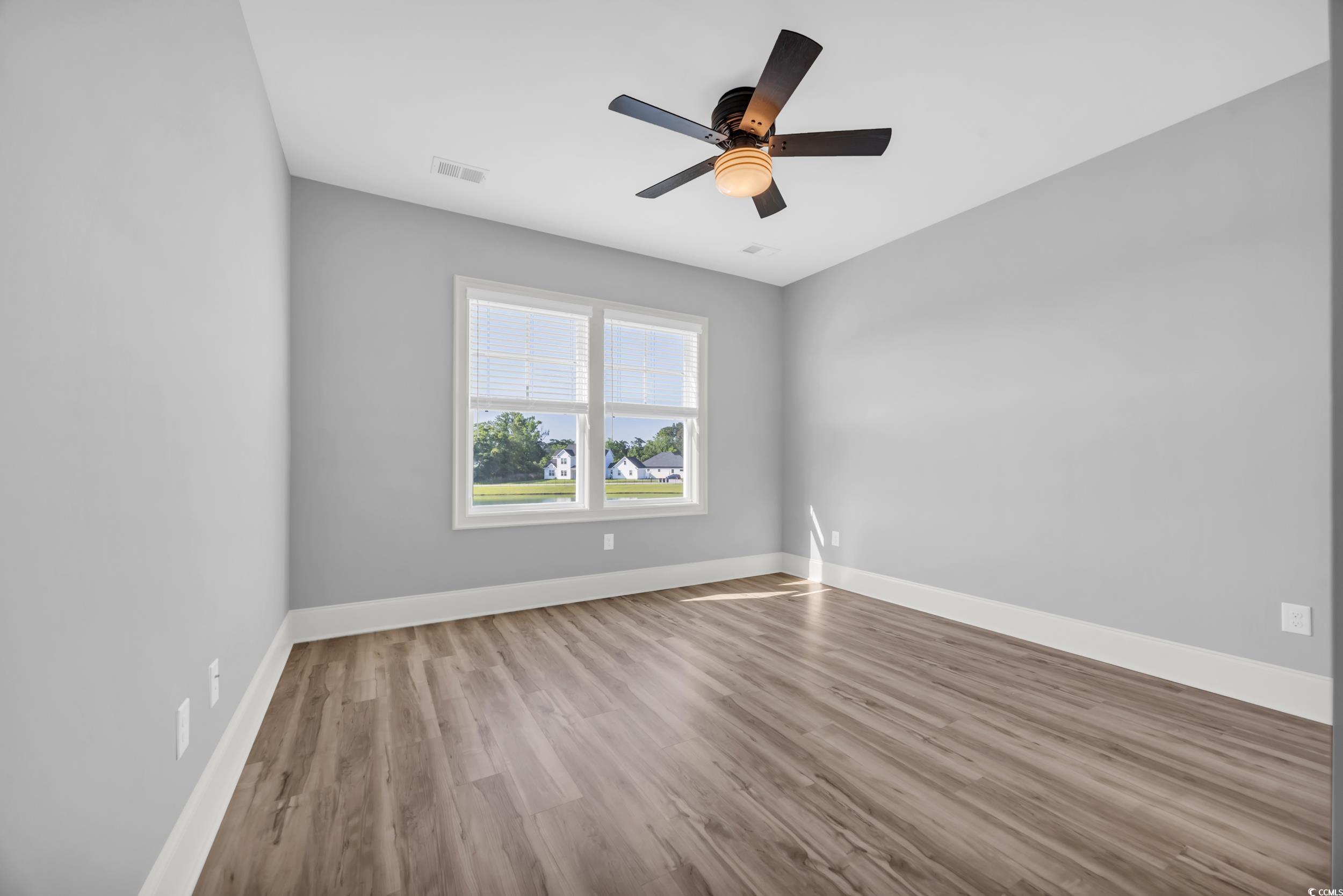 Spare room with wood finished floors, baseboards, and ceiling fan