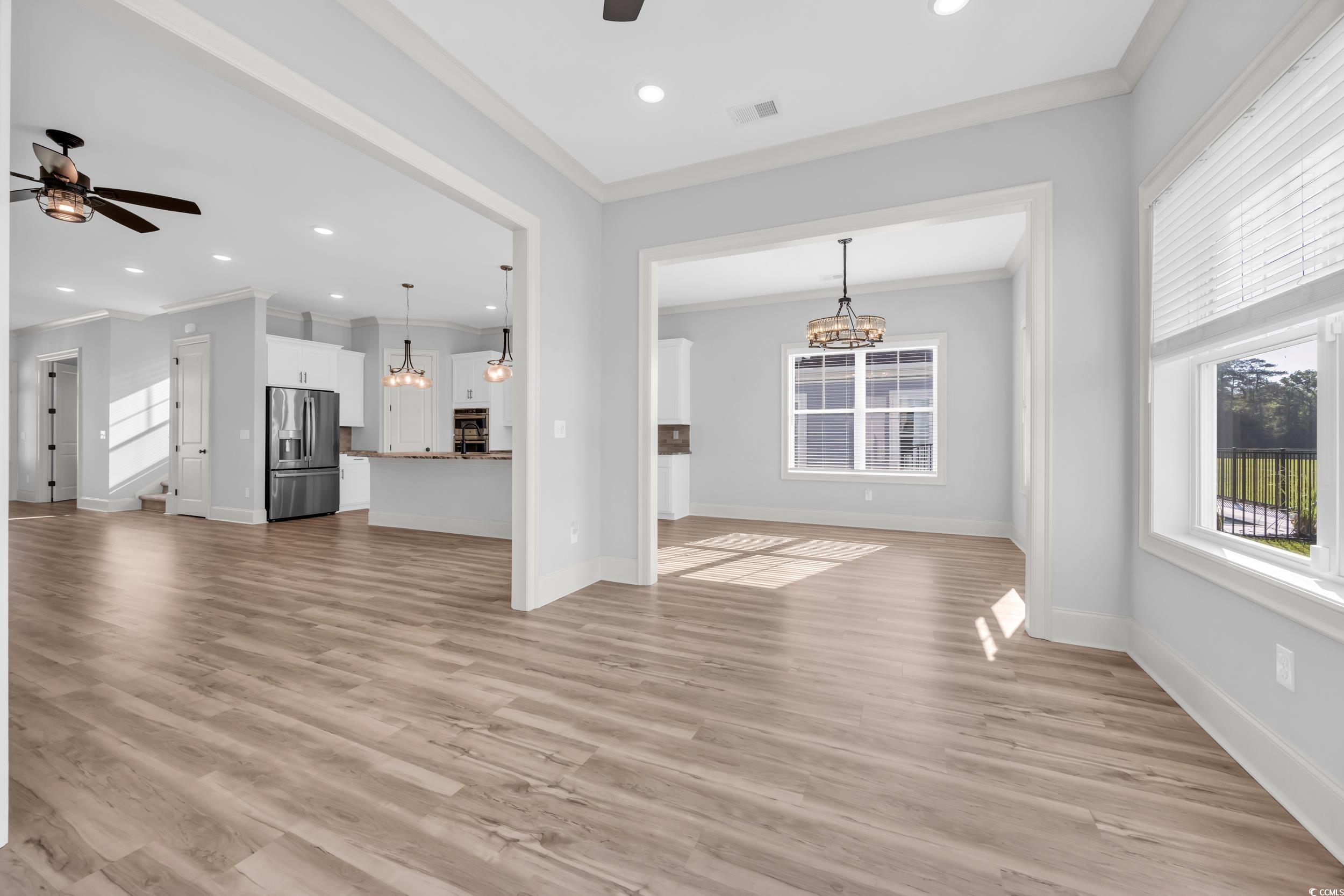Unfurnished living room with a ceiling fan, a chandelier, crown molding, baseboards, and recessed lighting