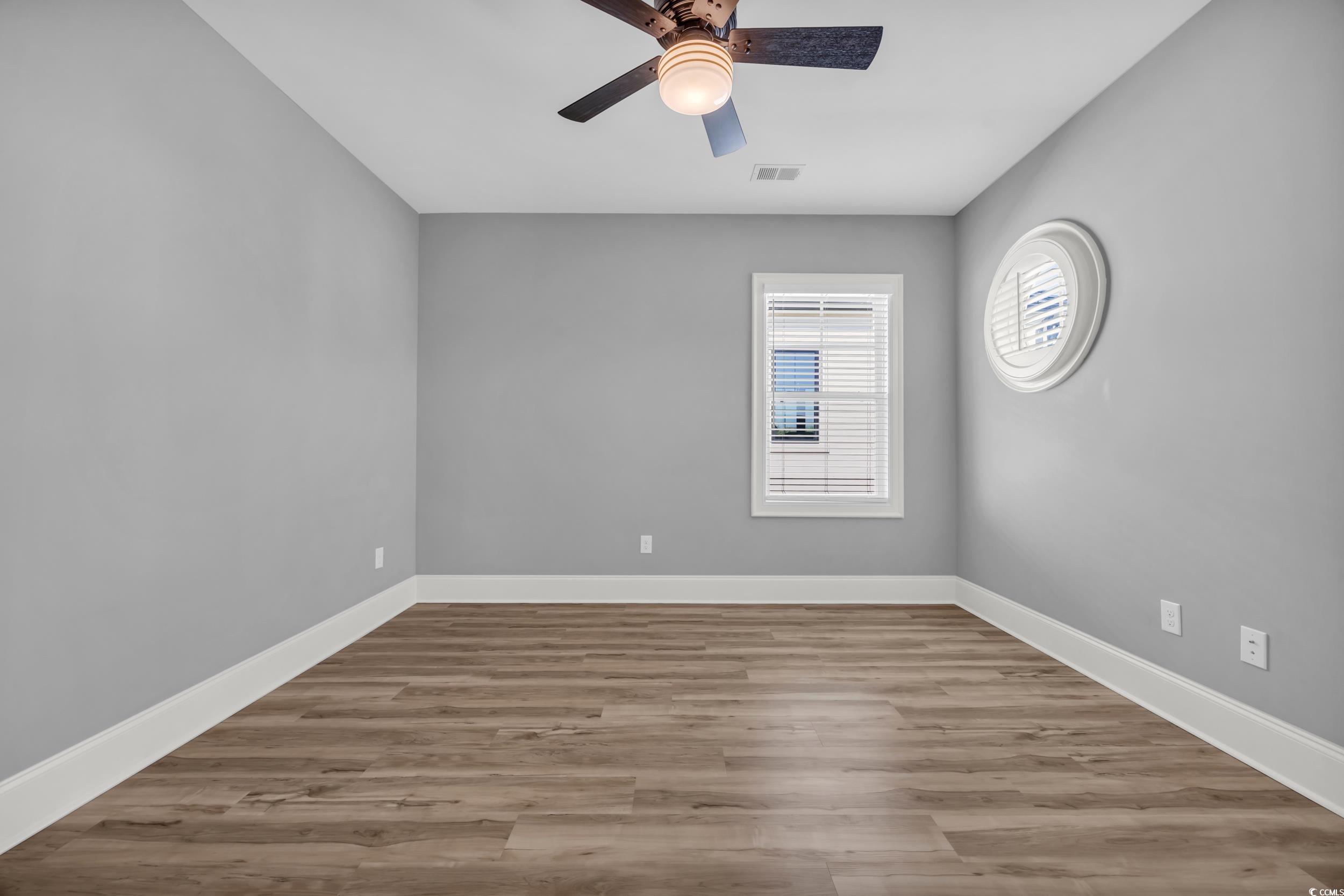 Unfurnished room with ceiling fan, baseboards, and wood finished floors