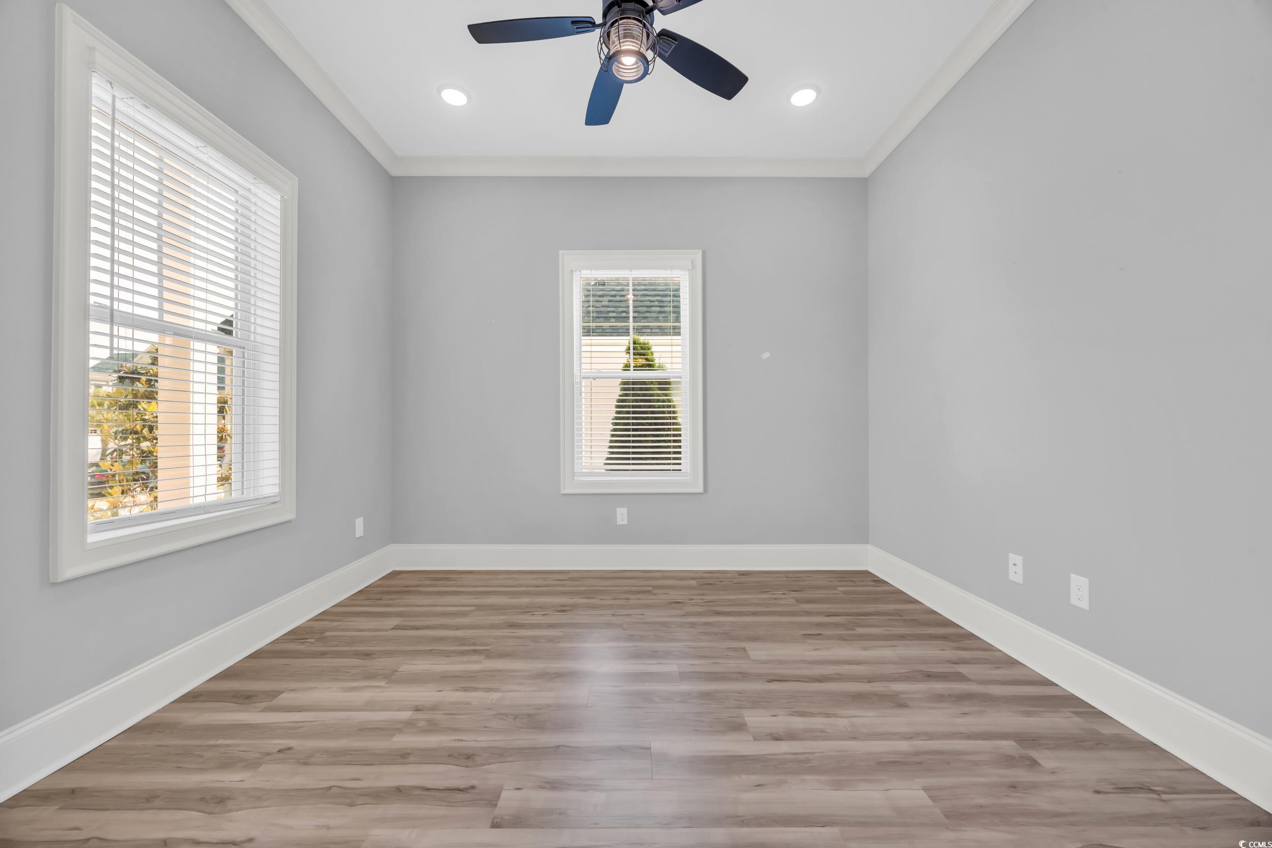 Empty room with a ceiling fan, baseboards, light wood finished floors, crown molding, and recessed lighting