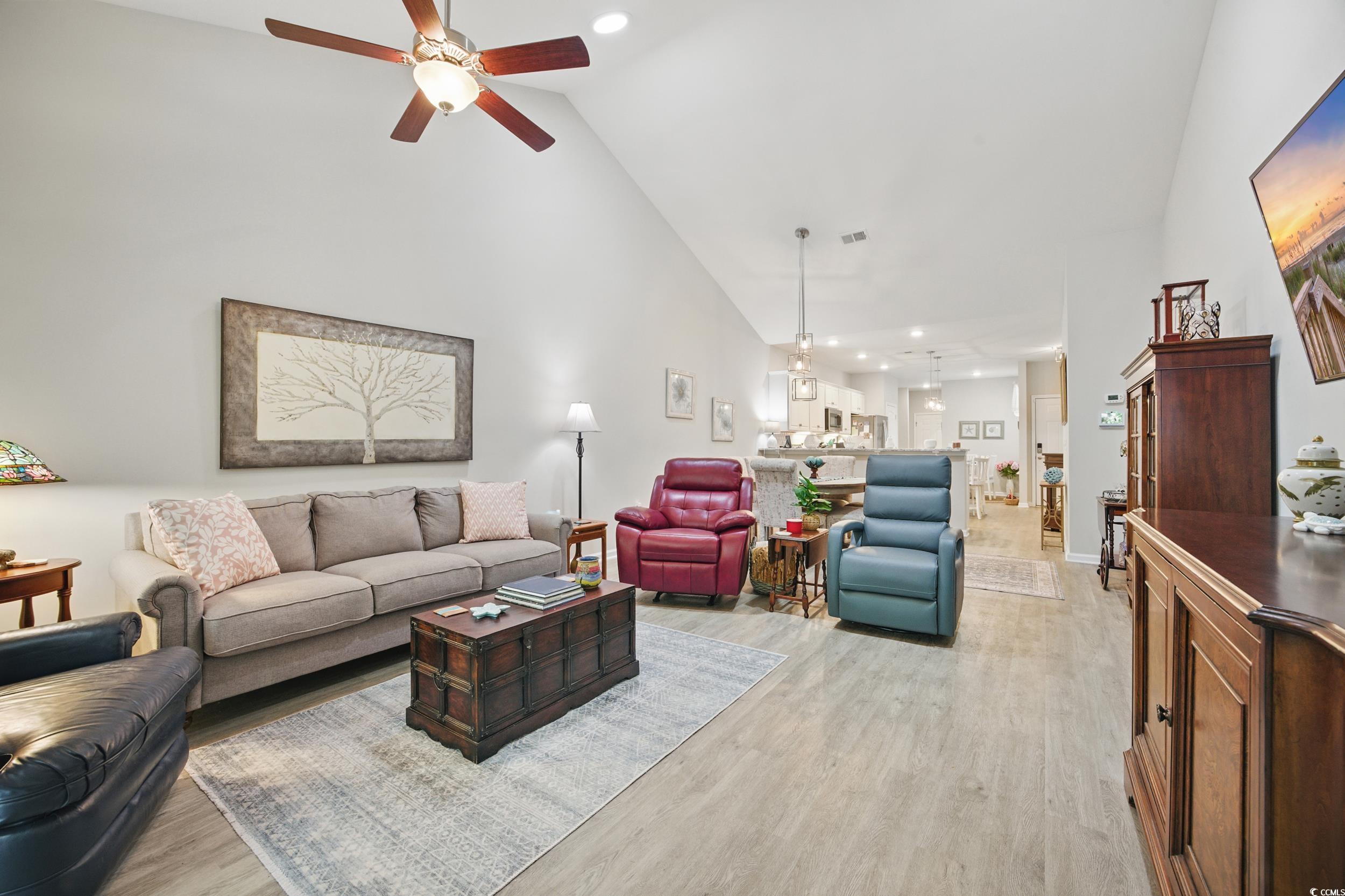 Living room featuring a ceiling fan, high vaulted ceiling, light wood finished floors, recessed lighting, and baseboards