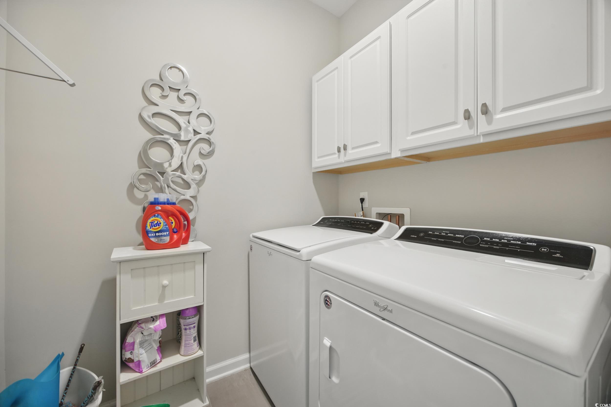 Laundry room with independent washer and dryer, baseboards, and cabinet space