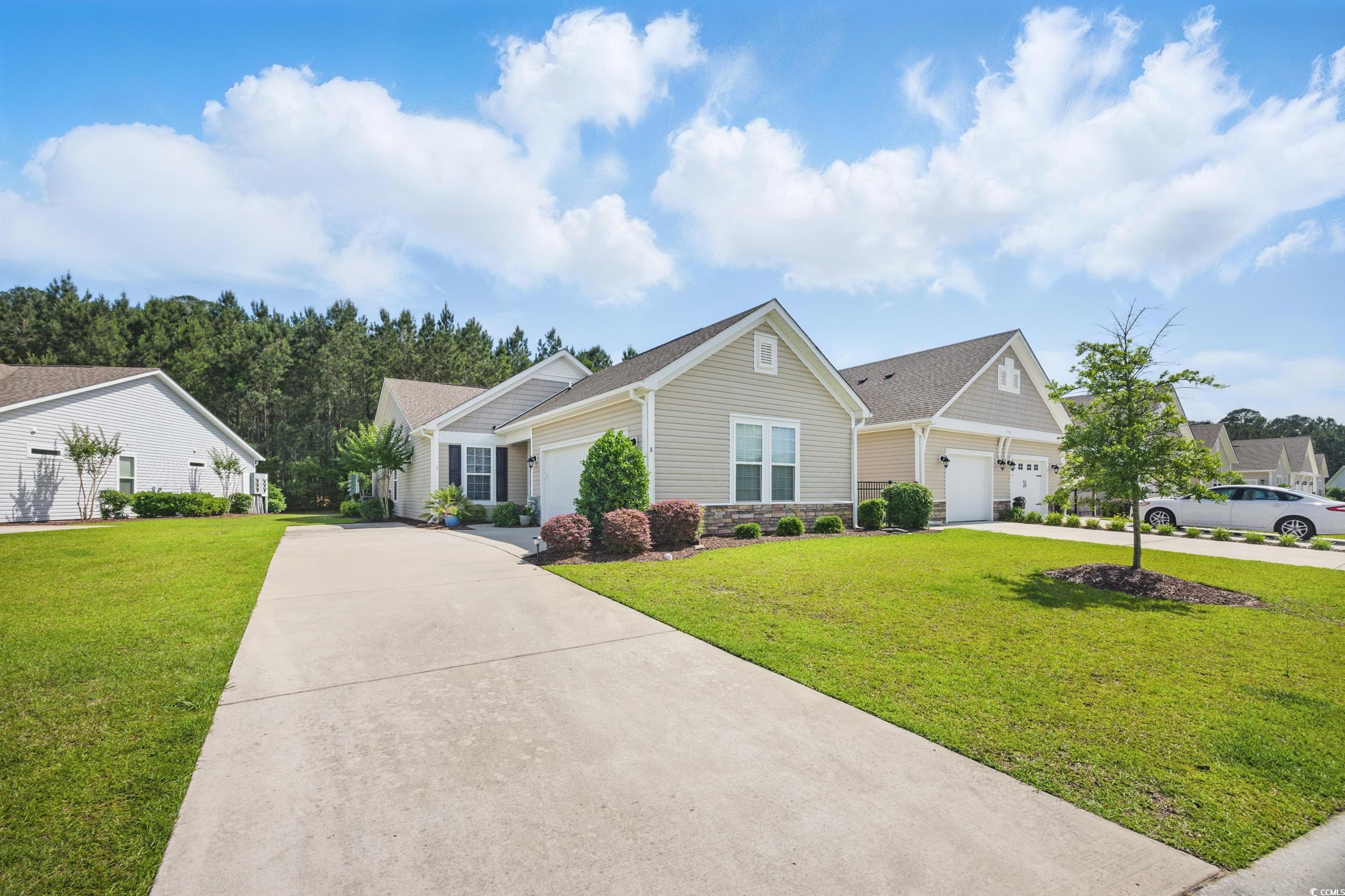 View of front of house featuring driveway, a garage, a front yard, and stone siding