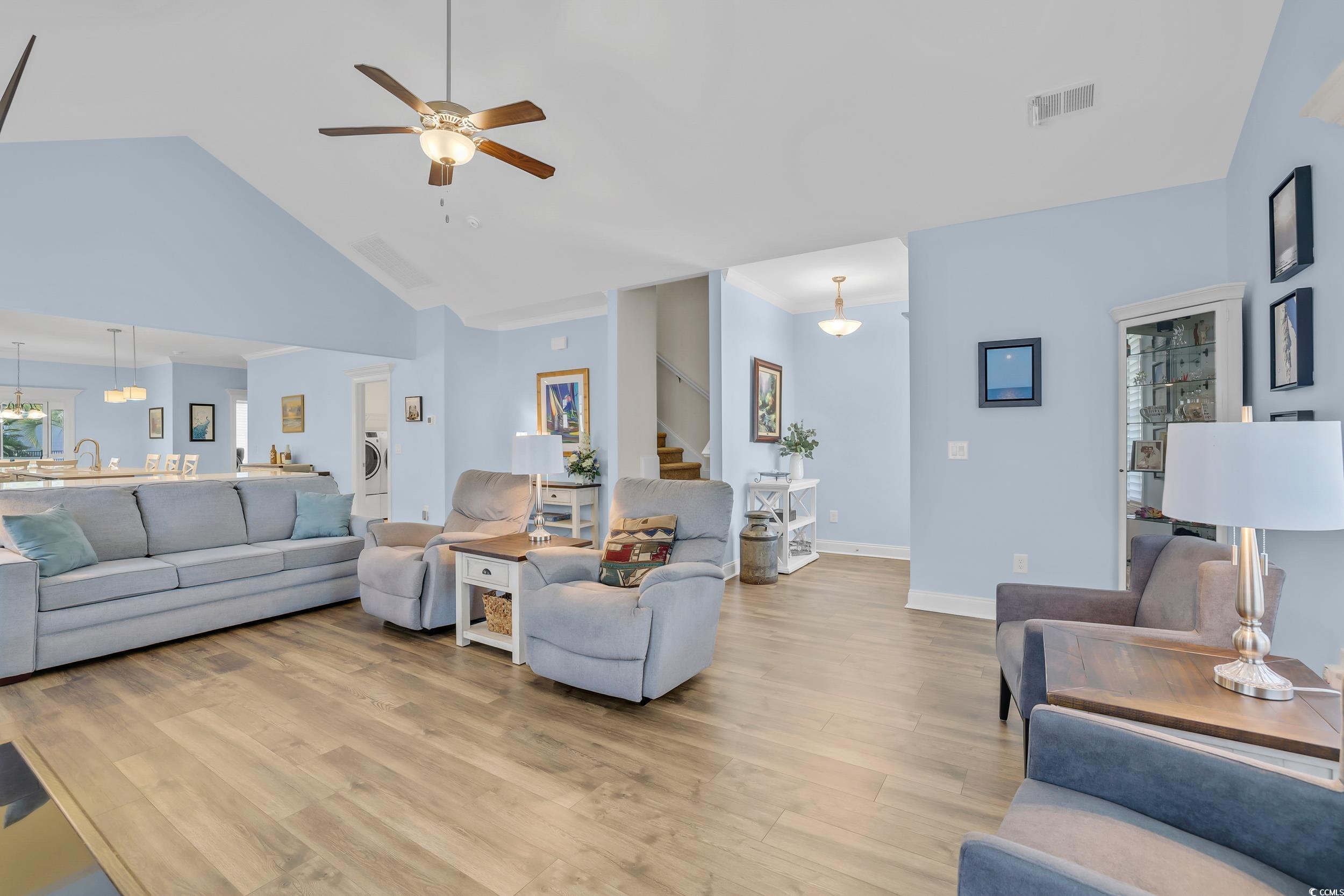 Living room featuring stairs, light wood-style flooring, ceiling fan, high vaulted ceiling, and washer / clothes dryer
