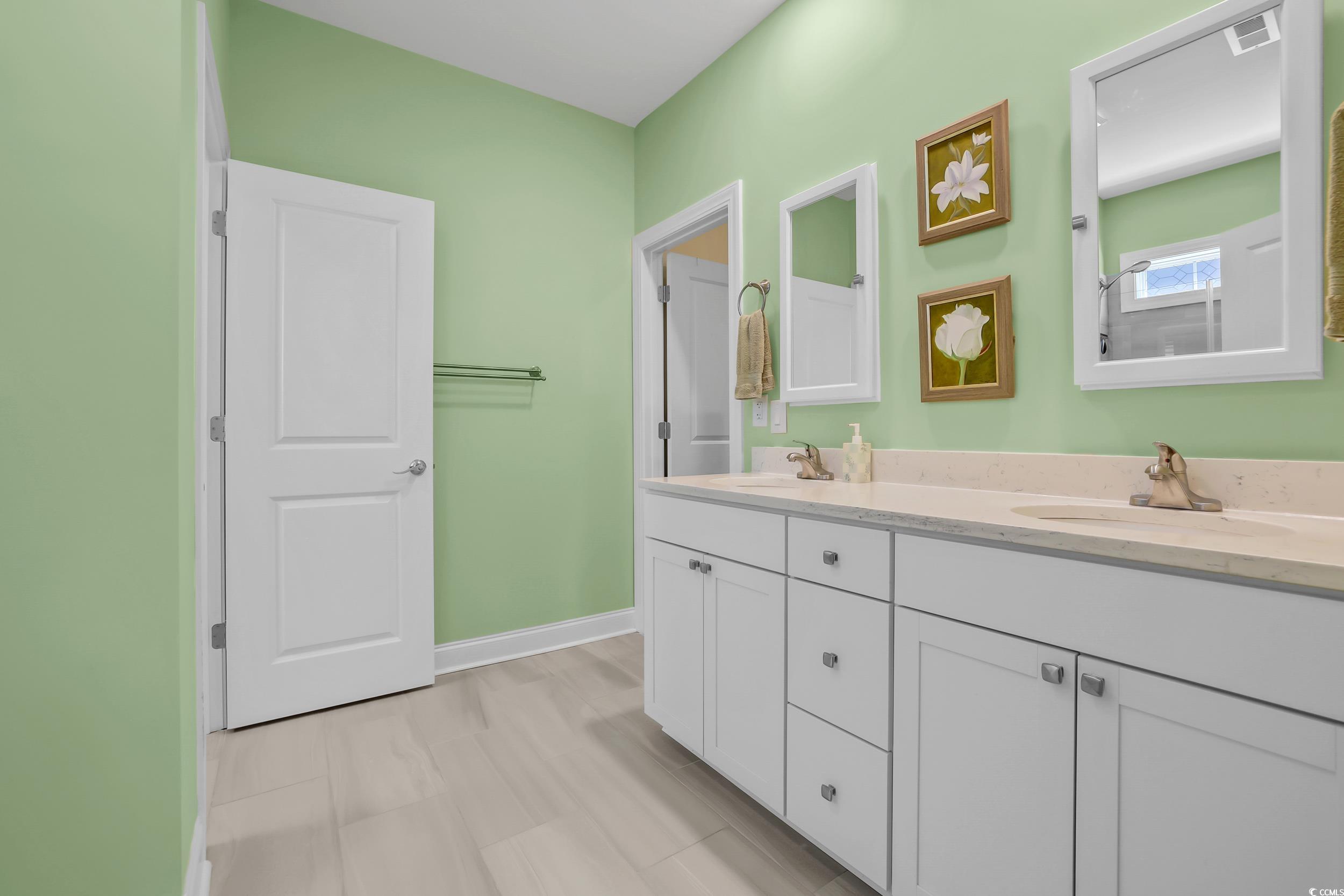 Bathroom with double vanity and baseboards