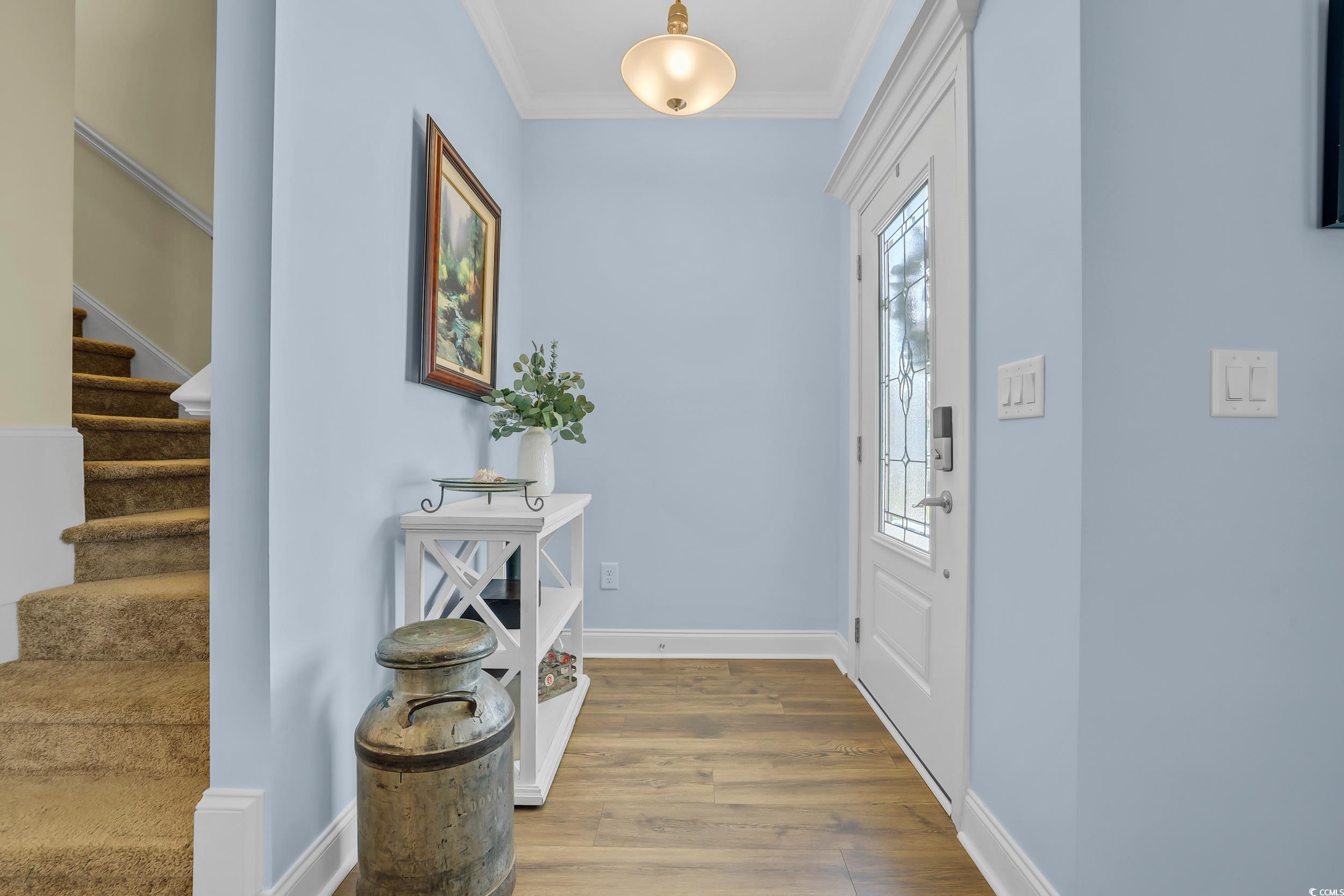 Entrance foyer with stairway, wood finished floors, crown molding, and baseboards