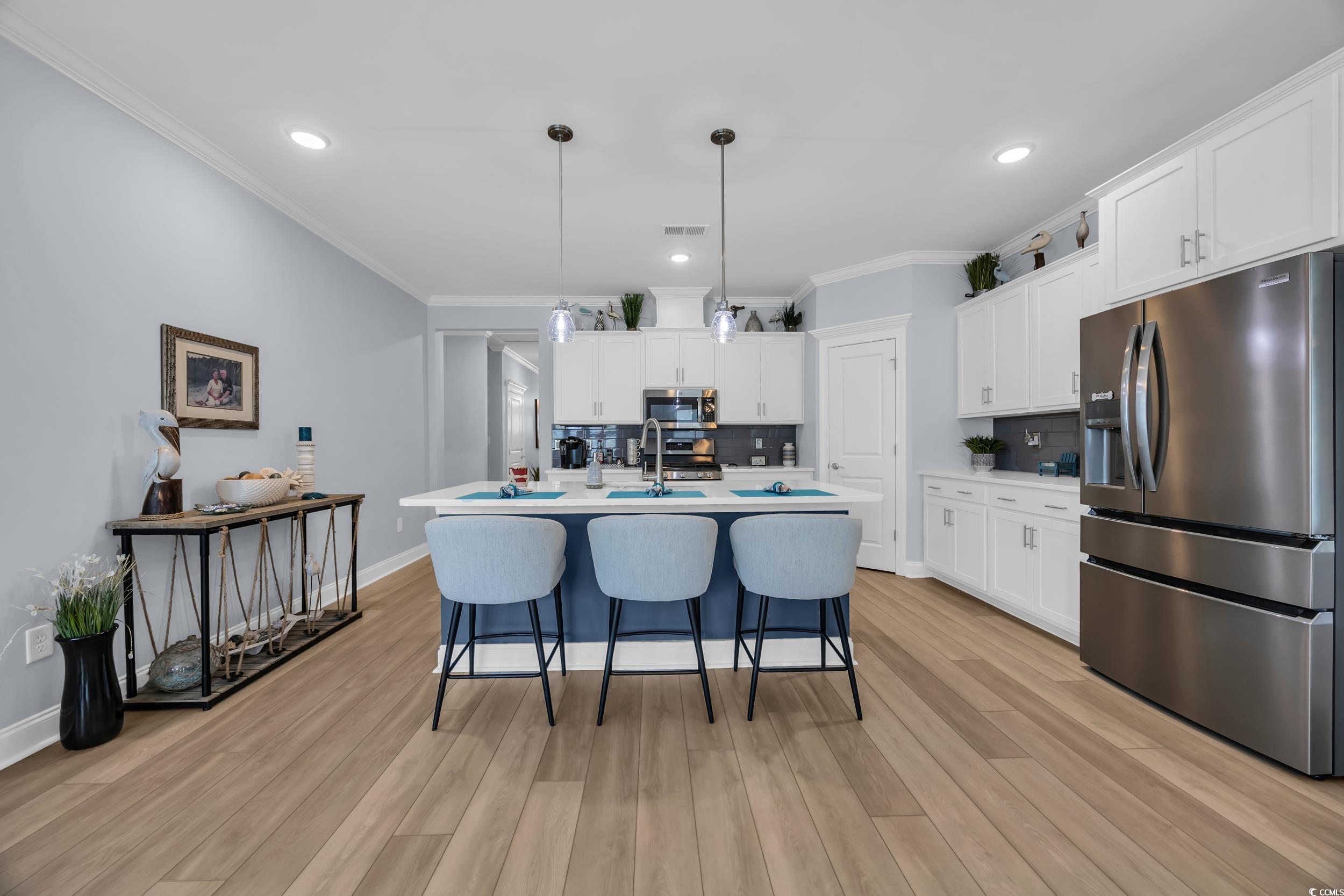 Kitchen with appliances with stainless steel finishes, decorative backsplash, a breakfast bar area, light countertops, and white cabinets