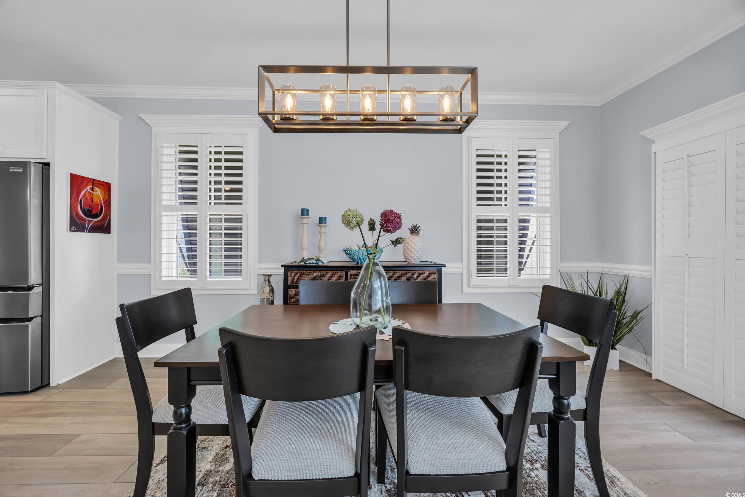 Dining area featuring a chandelier, plenty of natural light, light wood-style floors, and crown molding