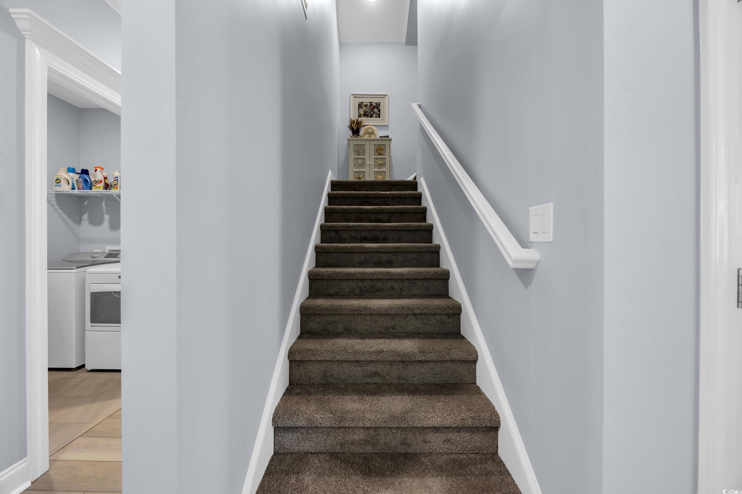 Staircase with washer and dryer, baseboards, and wood finished floors