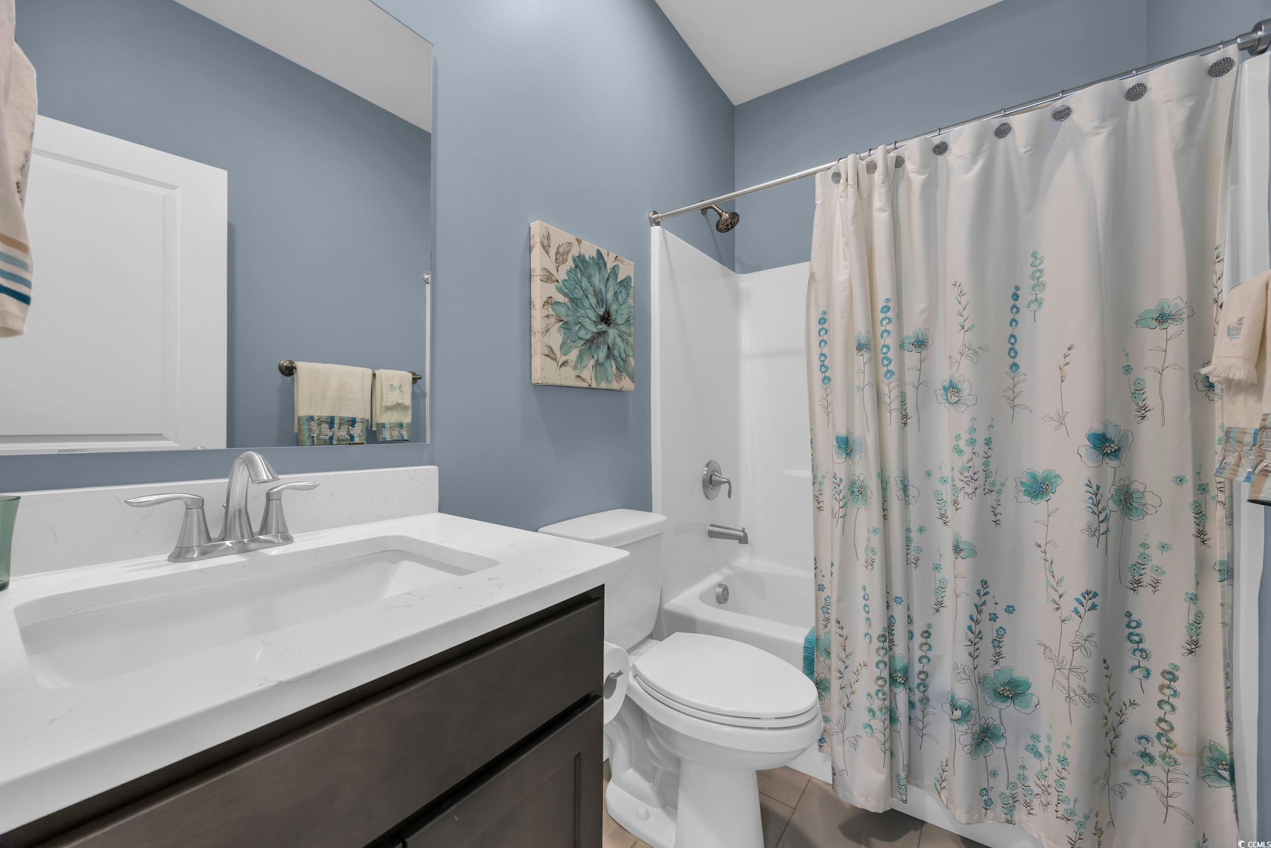 Bathroom with vanity, toilet, shower / tub combo with curtain, and tile patterned floors