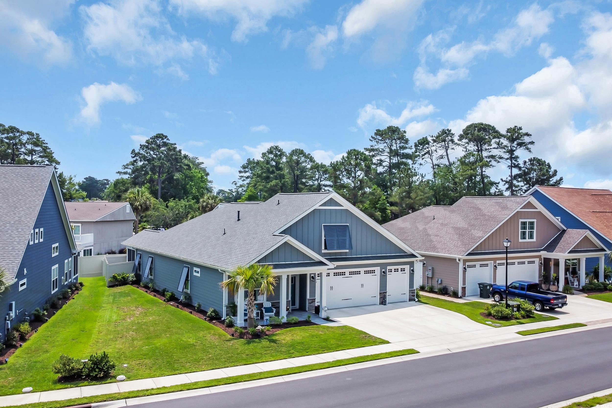 Craftsman inspired home featuring board and batten siding, concrete driveway, a front lawn, and roof with shingles