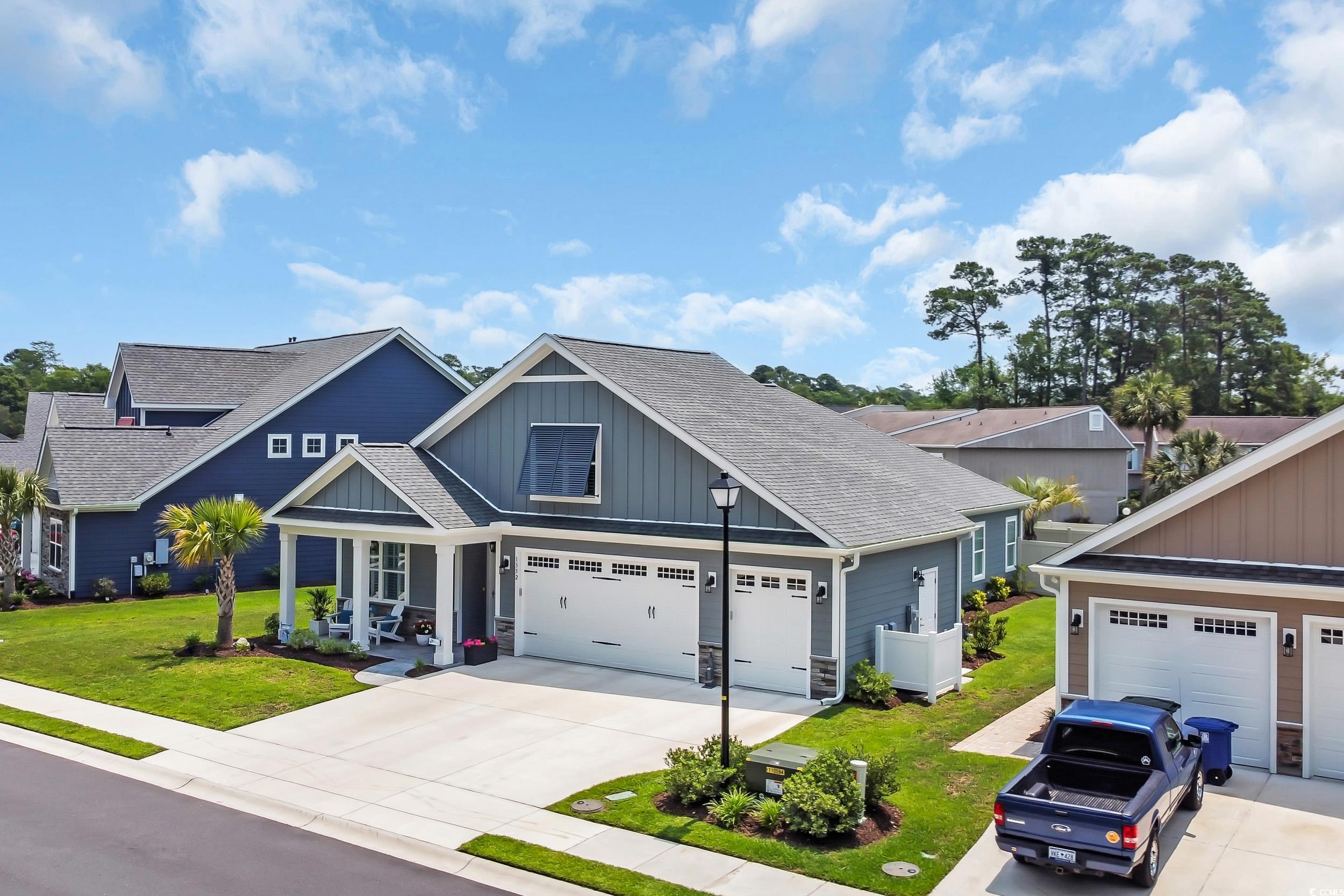 View of front of property with board and batten siding, roof with shingles, driveway, and a front yard