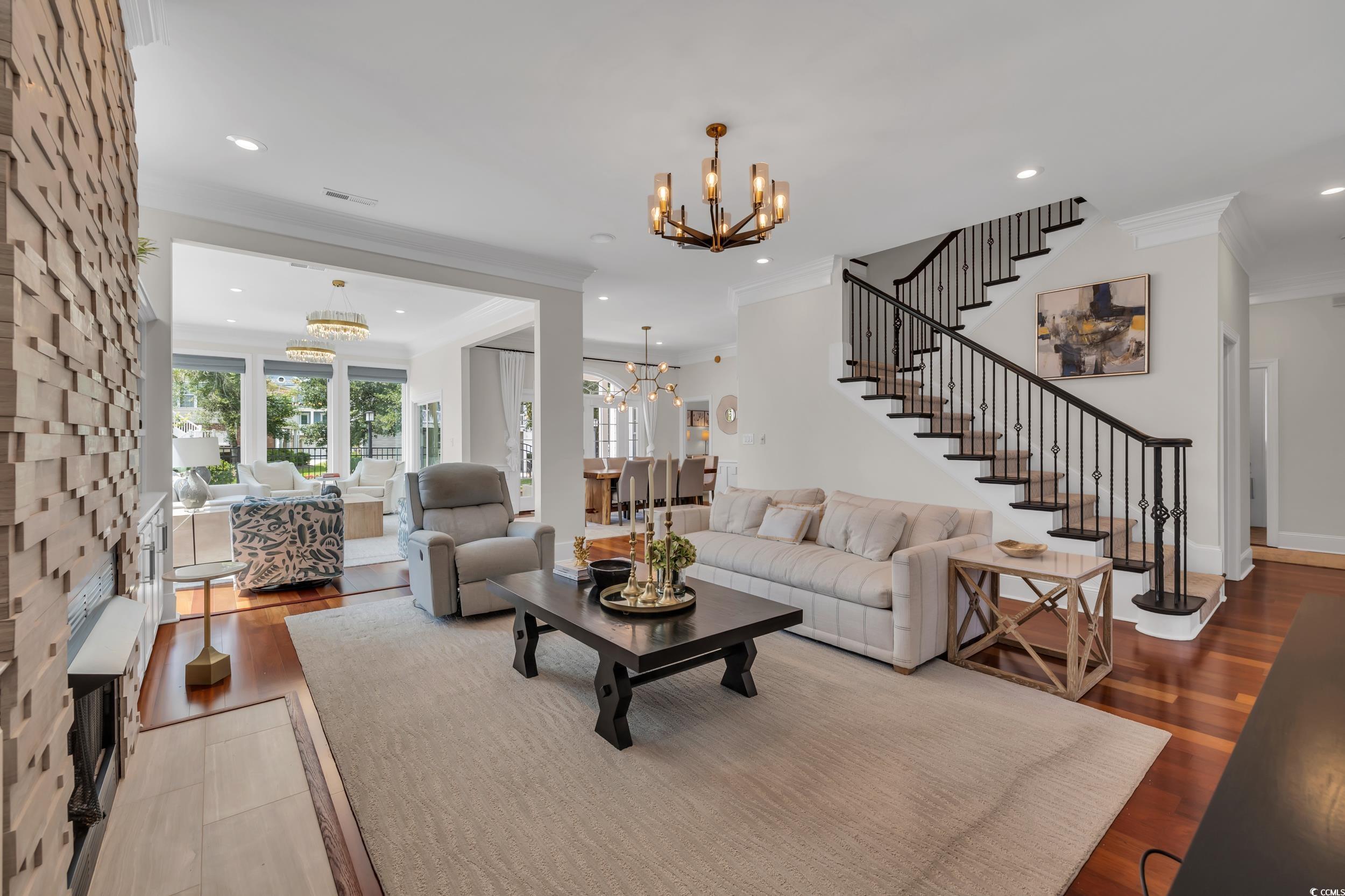 Living area featuring a chandelier, crown molding, recessed lighting, wood finished floors, and stairway