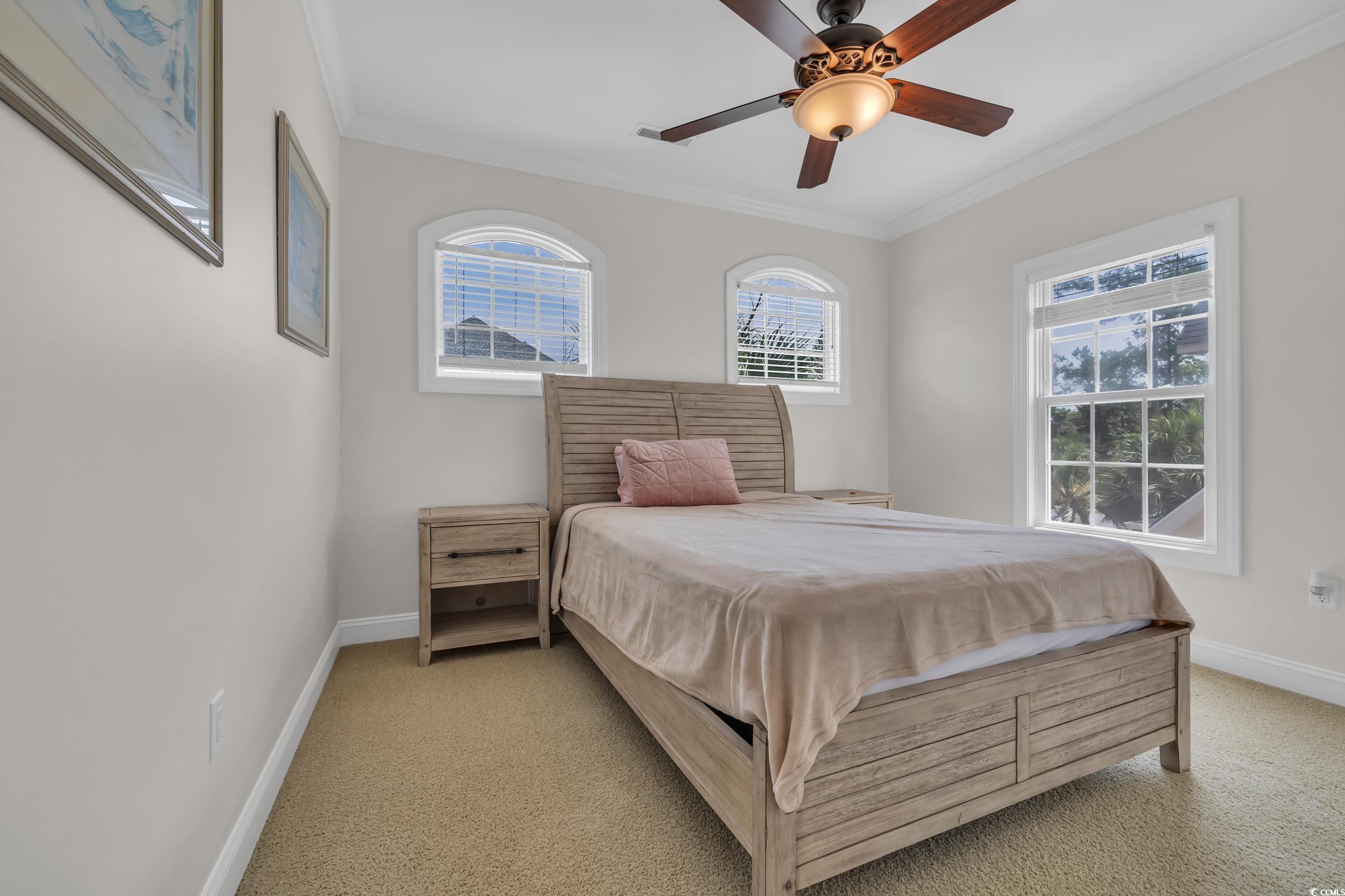 Bedroom featuring light carpet, ornamental molding, baseboards, and ceiling fan