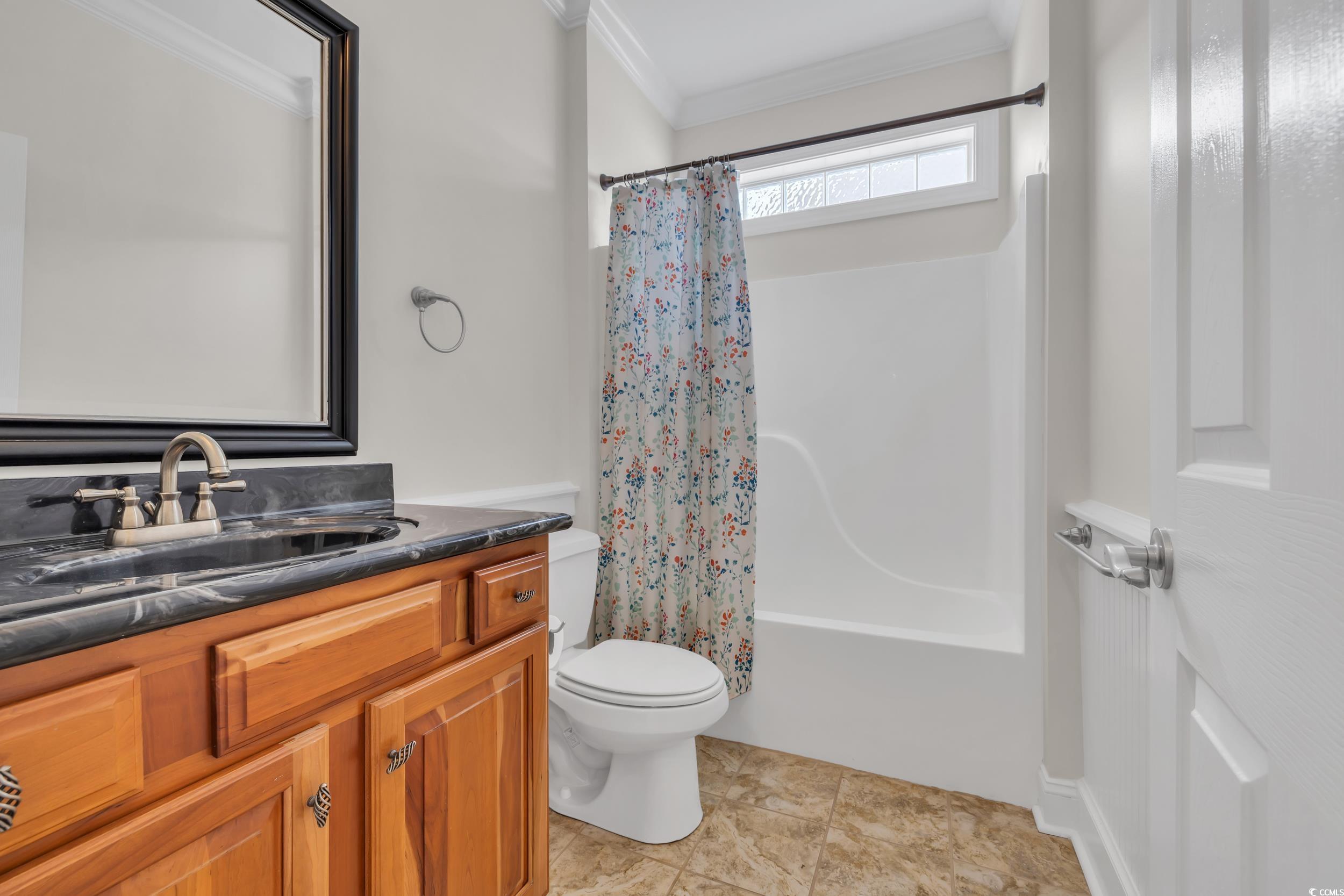 Bathroom featuring crown molding, vanity, shower / tub combo, toilet, and tile patterned floors
