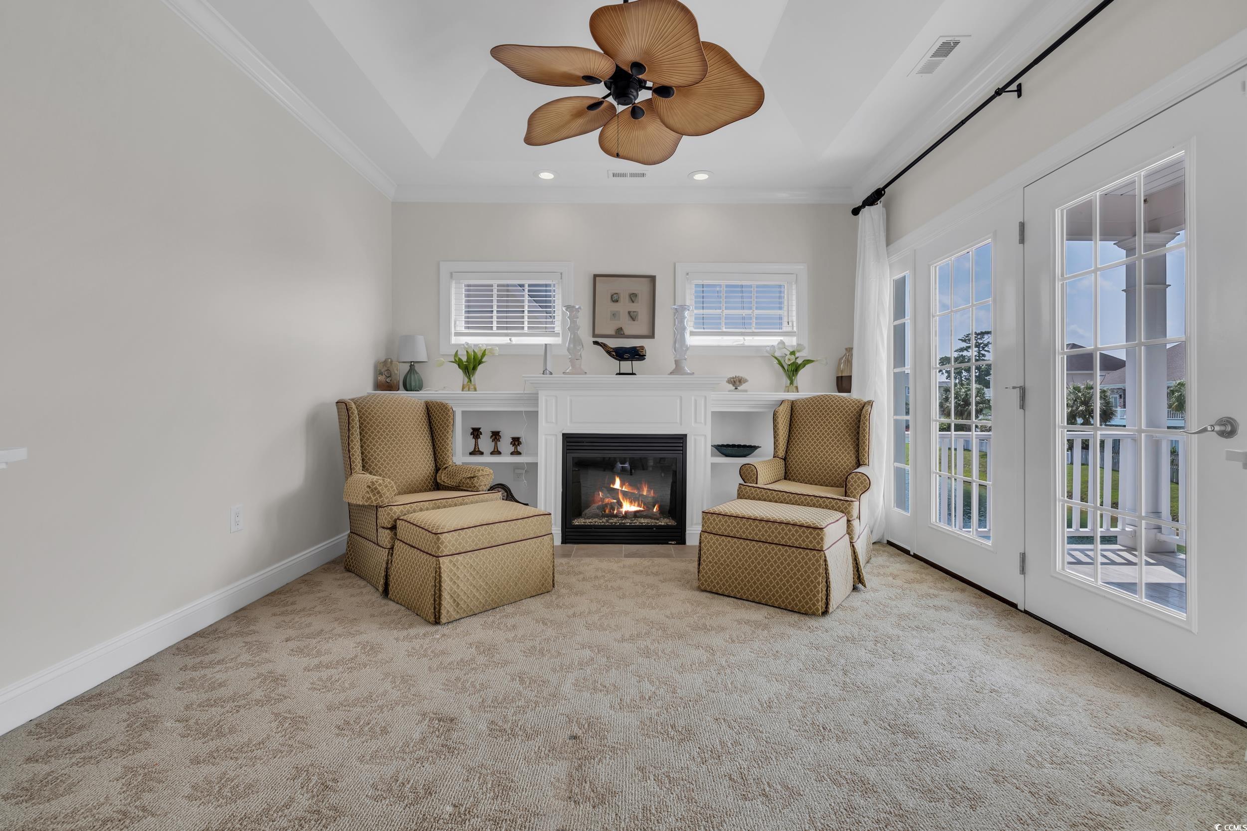 Living area featuring carpet floors, a glass covered fireplace, crown molding, ceiling fan, and recessed lighting