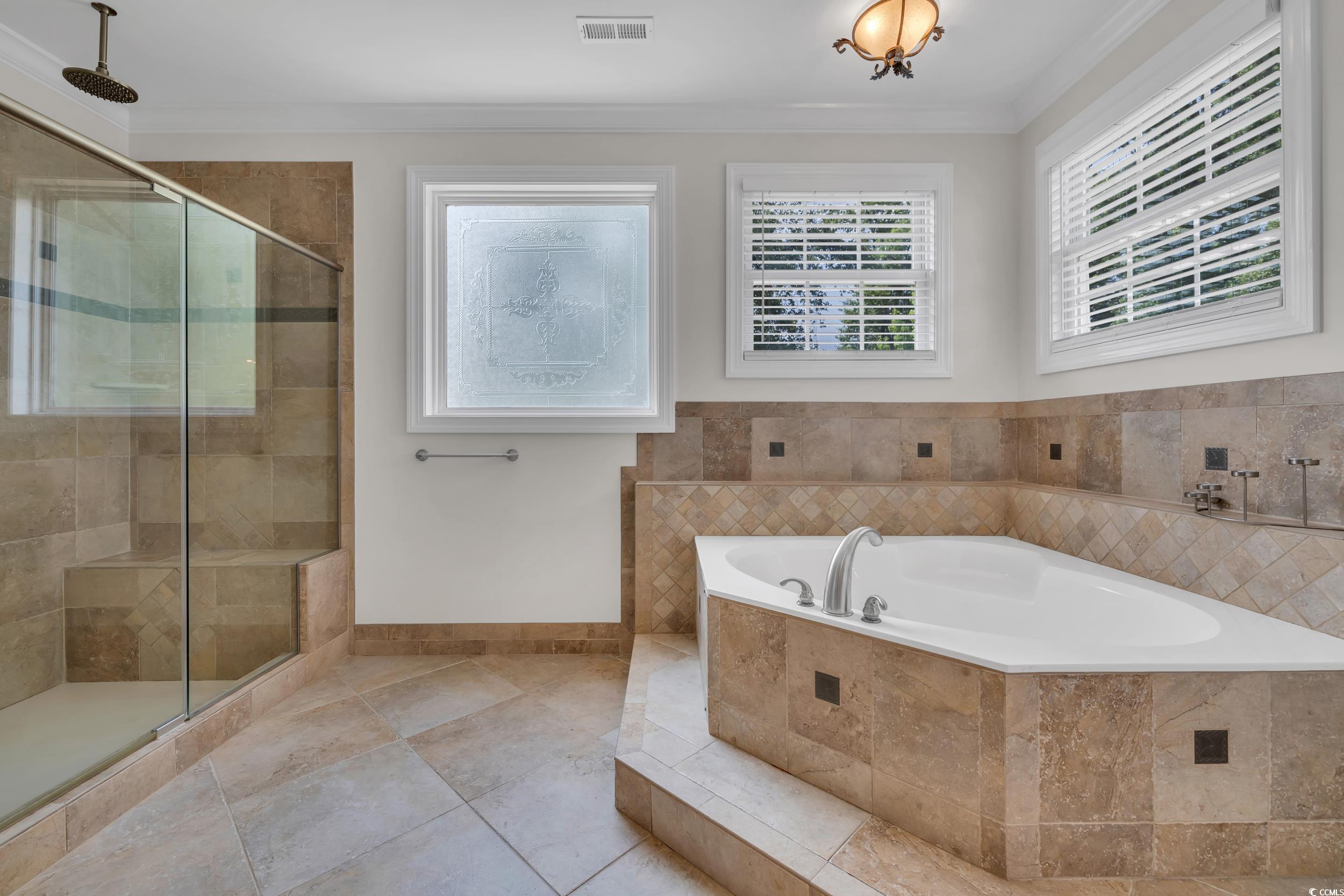 Bathroom with a bath, a shower stall, crown molding, baseboards, and tile patterned floors