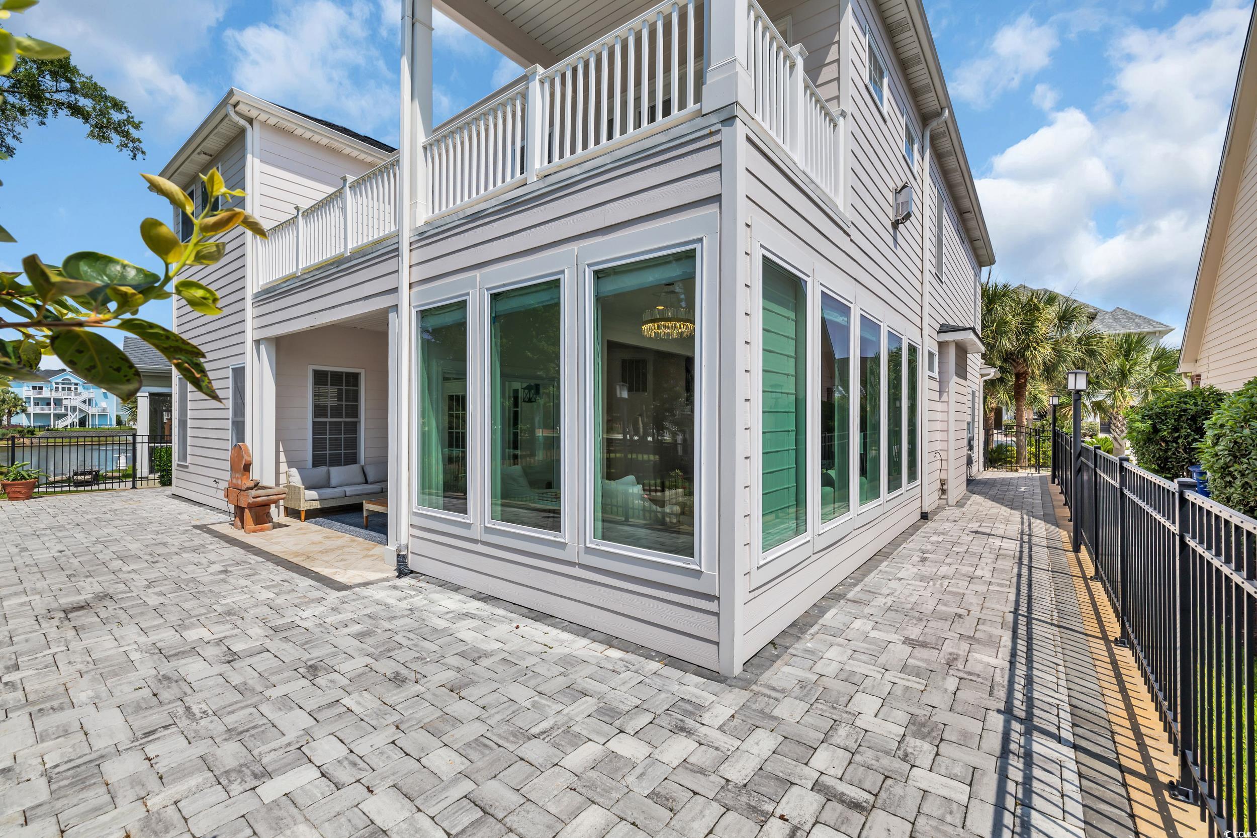 View of side of home with a balcony, a fenced backyard, and a patio