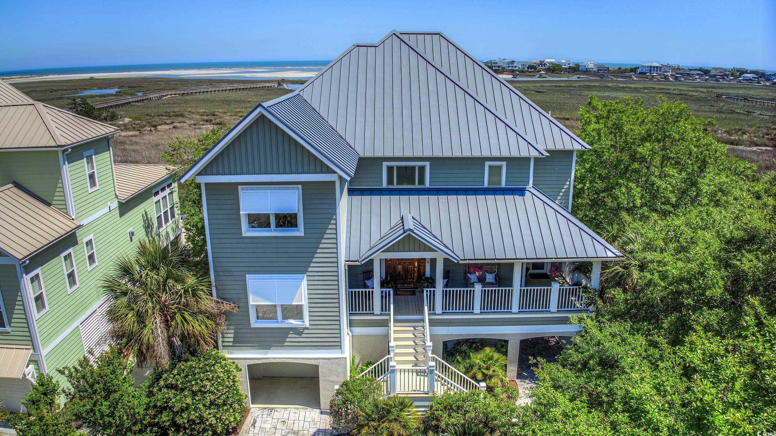 want a home with truly spectacular views? you just found it!! this custom designed, coastal inspired, creekfront 5 bedroom, 5.5 bath home provides some of the best views of the creek, marsh, pawleys north inlet and atlantic ocean that you will find. enjoy sunrise over the ocean, views of the changing tides in the inlet and birds at play over the water. the views from this home change by the hour as the tide ebbs and flows through pawleys north inlet. this home has custom features throughout to include heart of pine flooring, solid wood doors and a custom heart of pine four level open staircase. there is also an elevator to take you from the ground level at garage to the third level of the home. the fourth level is a loft area or home office with an open sundeck. the first floor is the main entry from front porch and has 4 bedrooms, 4 bathrooms and 2 bedrooms are on ocean side of home. the first floor has its own family room, custom full wall length-built ins with fireplace and the main laundry area. the 2nd floor is the main living area of the home and has a custom designed kitchen that includes a large work island with gas cooktop, breakfast bar, all built-in stainless steel appliances with sub zero refrigerator, double wall ovens, wine fridge, microwave, dw and a farm sink. solid surface quartz / granite countertops and pantry. the kitchen is open to the dining area and 2nd floor family room with custom built ins and fireplace. this is the main gathering place of the home and is open to the 2nd floor screen porch, covered porch and open deck, all offering views of the pawleys waterfront that make this home so special. the primary bedroom suite is also located on the main floor (2nd) and has fantastic views, 2 closets, dressing area and primary bath includes a jetted tub, walk in tile shower and a 2nd washer and dryer conveniently located next to the bathroom. this home was designed with lots of windows to allow the carolina sunshine in and provide 180 degrees of views from multiple levels of the home. the location of the porches and decks on all floors adds to the coastal feel of this home allowing a great flow from indoors to outdoors. there are 2 screen porches, 2 covered porches and 2 open deck areas on ocean side of the home. there is also a wrap-around front porch. the garage area under the house provides ample parking for vehicles, abundant storage and an outdoor shower and downstairs toilet. enjoy your private saltwater swimming pool and a hot tub and or take a walk to the community dock for fishing, crabbing or just sit and enjoy the waterfront under the covered dock. launch a kayak and cruise the inlet and marshes or paddle over for a day at the uncrowded beaches and at pawleys north inlet. this property offers many different coastal water activities right at home in your backyard. located in sweetgrass, a gated waterfront community with community boardwalk, covered dock and floating dock on pawleys inlet. be sure to view the 3d floor plan walk thru ( https://my.matterport.com/show/?m=beqrlcsbymj&mls=1 ) ..... and the video ( https://www.youtube.com/watch?v=uvnlidaksu4 ) that shows the location and a complete aerial view of the community dock, inlet and beaches. schedule your private showing today! come see this exceptional home and see what makes this location truly special.