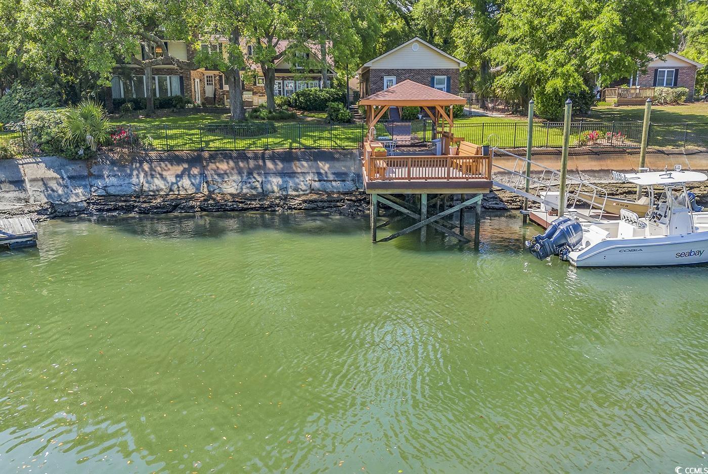 this is a highly desirable waterfront home in the fabulous neighborhood of mt. gilead. one of the largest and highest elevation lots in the area featuring gorgeous live oak trees. property has brand new large covered lumberock stationary dock with fish cleaning station and also a floating dock with commercial grade dock boxes. dock includes winch for storage of small boat. beautiful view of the deep water protected canal that is a short boat ride to the inlet and atlantic ocean. the home boasts a renovated kitchen, 4 bedrooms/ 4 1/2 bathrooms, hearth room with fireplace, theatre room with projection screen tv, game room, large carolina room with expansive views of the waterfront, and oversized detached two car garage. the theatre room can be converted to a fifth bedroom.  you will want to be outside all of the time with this beautiful backyard overlooking the water. the large outdoor patio boasts an outdoor grilling area station with a fire magic grill and seating area with a custom gas fire pit. of course, with your boat in your backyard, it's easy to take an evening cruise to have dinner on the marshwalk of murrells inlet, 20 minutes to the ocean for deep-sea fishing or relax on beach at the local's favorite beach called "the point". fully-fenced backyard makes it easy for your pups to enjoy all of the outdoor amenities, as well.