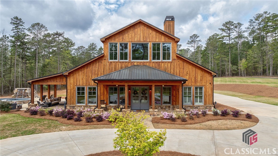 Your opportunity to own one of the most unique and gorgeous properties in Oconee County! Located in the middle of 12 acres of beautiful Pines and hardwoods off Colham Ferry Rd. is an amazing ALL WOOD FRAMED BARNDOMINIUM. This stunning home has every upgrade and bell and whistle. The luxury kitchen is complete with a Thermador range, pot filler, custom vent hood and cabinetry, quartz countertops, oversized island with apron front sink, custom walk-in pantry and Pebble Ice Maker. Enjoy the wonderful covered porches that overlook the Gunite, Pebble-Tec Salt Water Pool complete with a waterfall, jumping rock and heated spa. In progress is the construction of a pool house with an 18ft. Masonry fireplace, stubbed for bathroom and kitchen.     From the moment you enter the gates of this breathtaking property you will be captivated by the details. Enter the home through the stunning wood and glass double doors and immediately, you will be taken with the immense, 26ft. vaulted, wood beamed ceilings of the family room, floor to ceiling stone fireplace, and 5 inch, Red Oak hardwood floors. The open concept of the family room, dining room, and kitchen lends itself to hosting all your family and friends for celebrations and holidays. Want to continue the entertainment after dinner?  Head out to the side covered patio and enjoy the spectacular outdoor spaces including a resort style pool, spa and waterfall, or better yet, start your summer barbecues here!    Off from the kitchen and family room, you'll find the Primary Suite complete with a wood,vaulted ceiling, expansive primary bath offering its own washer and dryer, not one, but two generous custom walk-in closets, and the most amazing shower, you just have to see to believe! Connected to the back walk-in closet is a separate room, perfect for an office, nursery or an extension of the closet.     The main level boasts a lovely half bath, two more generoous ensuite bedrooms with beautifully tiled showers and heated toilet seats! One bedroom also provides a separate sitting/tv room.   Walk upstairs to discover a child/teen's dream! The expansive ensuite bedroom with its own oversized walk-in closet also leads to an over 780 sq.ft. bonus room/living room/playroom/office/media room.    If the living and outdoor spaces of this home weren't enough, wait until you see the over 2000 sq.ft. garage! This space will hold 4+ vehicles, ATVs, lawn equipment, and still leave you tons of room for storage.      Additional features of this wonderful home are: plantation shutters, security system, including gate cameras and a gate call box, smart home remote features, wood windows, metal roof, Trane High Efficiency HVAC units, spray foam insulation in walls & ceiling, continuous hot water, upgraded distraction system on well, and a back-up electric water heater, Spectrum Internet with Fiber Optics, and propane gas.    It just doesn't get better than a serene, secluded retreat situated in the Oconee County School System and close proximity to all things the Greater Athens Area has to offer! Don't miss your chance to own this splendid property!!