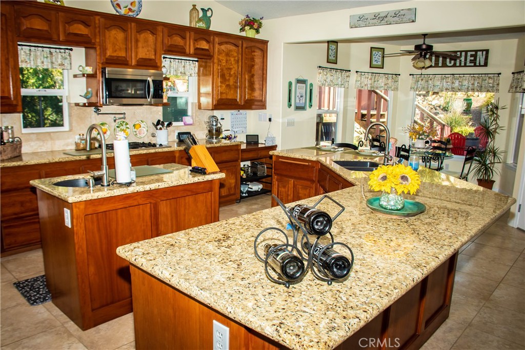 The kitchen has many amenities including granite counters, huge breakfast bar, island with sink, double oven, over the range microwave, travertine style flooring, built in cooktop, tile backsplash, pot filler, delta touch faucets, stainless appliances including the fridge, and a walk in pantry.