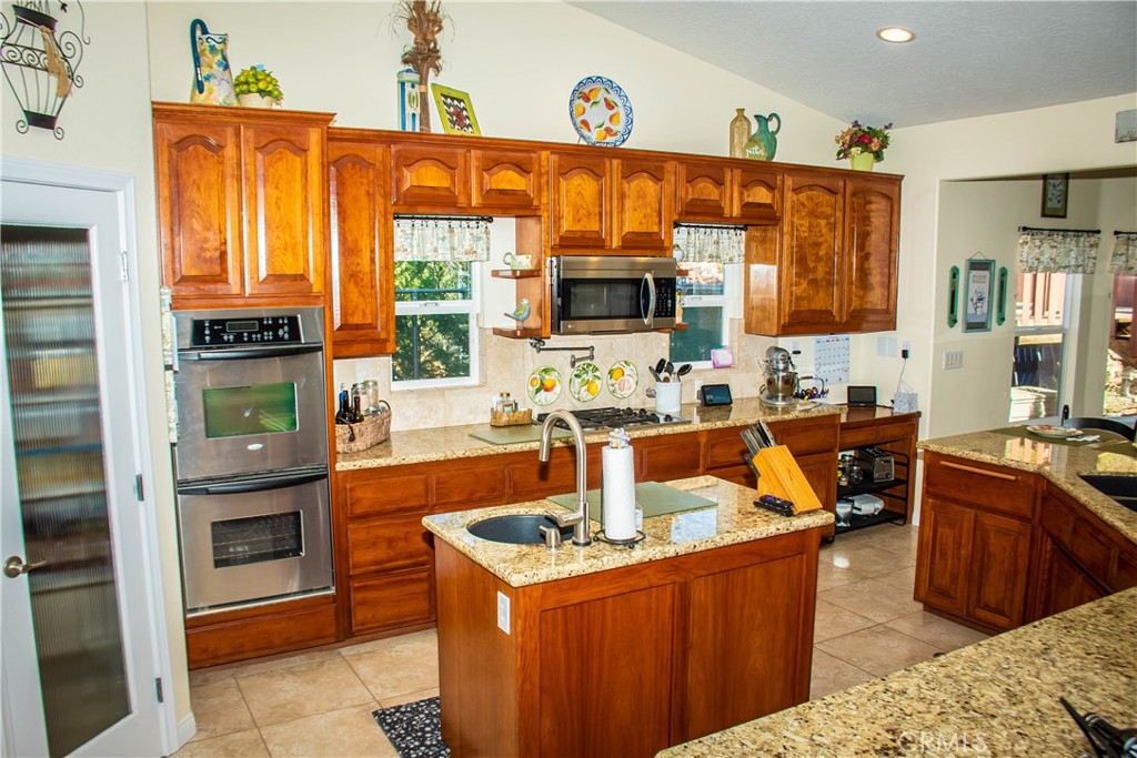 The kitchen has many amenities including granite counters, huge breakfast bar, island with sink, double oven, over the range microwave, travertine style flooring, built in cooktop, tile backsplash, pot filler, delta touch faucets, stainless appliances including the fridge, and a walk in pantry.