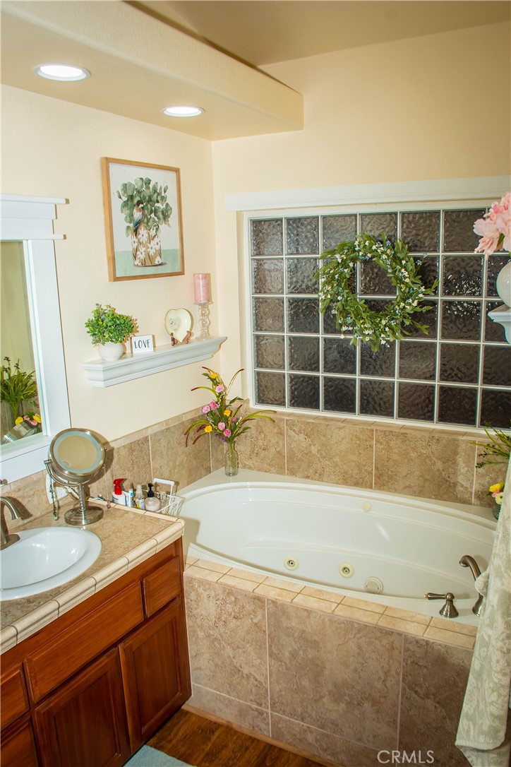 Primary bathroom includes a large jetted tub, dual sinks, separate tub and shower, shower with tile surround, updated light and faucet fixtures and a walk in closet.