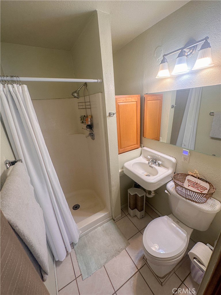 Guest house bath with shower, tile floors, and free standing sink.