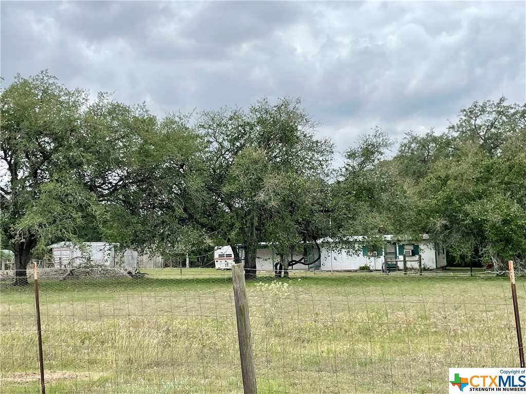 Whether you're looking for a peaceful weekend getaway or to downsize and simplify your lifestyle, this rustic cabin is a rare opportunity in the lovely, secluded Canyon Estates amidst the beauty of nature, and just 7 minutes from historic Goliad. Although there are no dedicated bedrooms, there are 2 rooms that could easily function as such, one of which with an attached bathroom (non-functioning at this time). The acreage, in addition to a plethora of lovely, mature oak trees, is fenced and cross fenced with 4 water spigots around the property, and an area which was previously used for Barbado sheep, along with a separate shop and storage container under one roof, an 8'x16' Morgan building, and a non-functioning travel trailer that Sellers will leave or remove, at the Buyer's discretion. This property is just waiting for your special touch and imagination. NOTE: black utility trailer is excluded; water well was rebuilt in 2021; and septic system was pumped in 2017. Property is being sold AS IS.