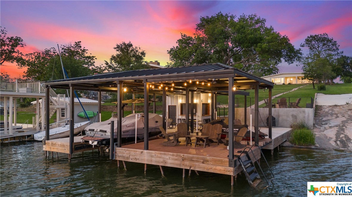 Welcome to your lakeside paradise on Lake LBJ! This 1.51-acre waterfront haven boasts 60’ of lakefront for endless aquatic fun. Launch a kayak or paddle board or set sail from the covered boat lift for a relaxing cruise. Effortlessly entertain guests on the oversized covered dock, complete with a bar shed featuring a kitchenette and bar seating. Or gather around the fire pit, the go-to spot for breathtaking lake views. Inside, cozy up by the wood-burning fireplace or step onto the covered back patio to unwind in the hot tub. The chef's kitchen dazzles with granite countertops, custom cabinets, and KitchenAid appliances. Enjoy dining while soaking in lake views from the sunroom. Your owner's suite is a sanctuary with a spa-like shower and outdoor access. The bunk room features built-in beds with lights and charging stations for your guests. This short-term rental-friendly home sleeps 14 comfortably. Minutes from sports courts and Sweet Berry Farms, your Lake LBJ retreat awaits!